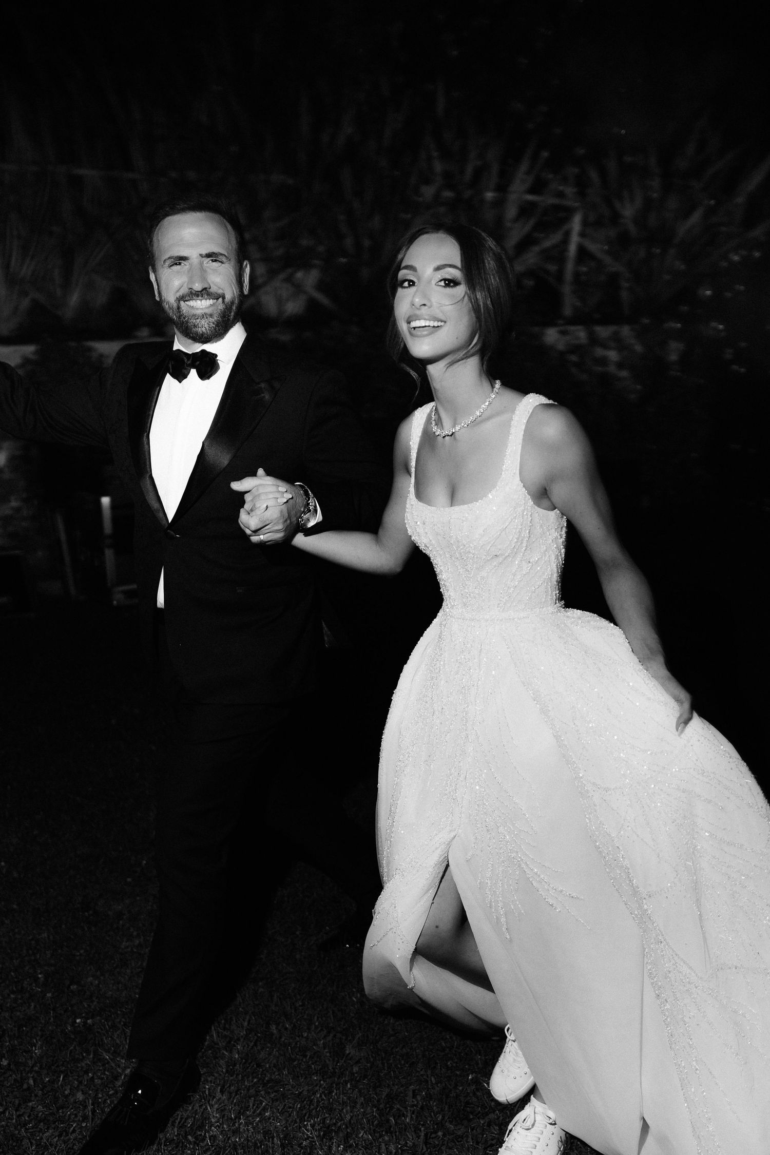 Black and white photo of a couple dancing at an elegant formal event with the woman wearing a flowing white dress.