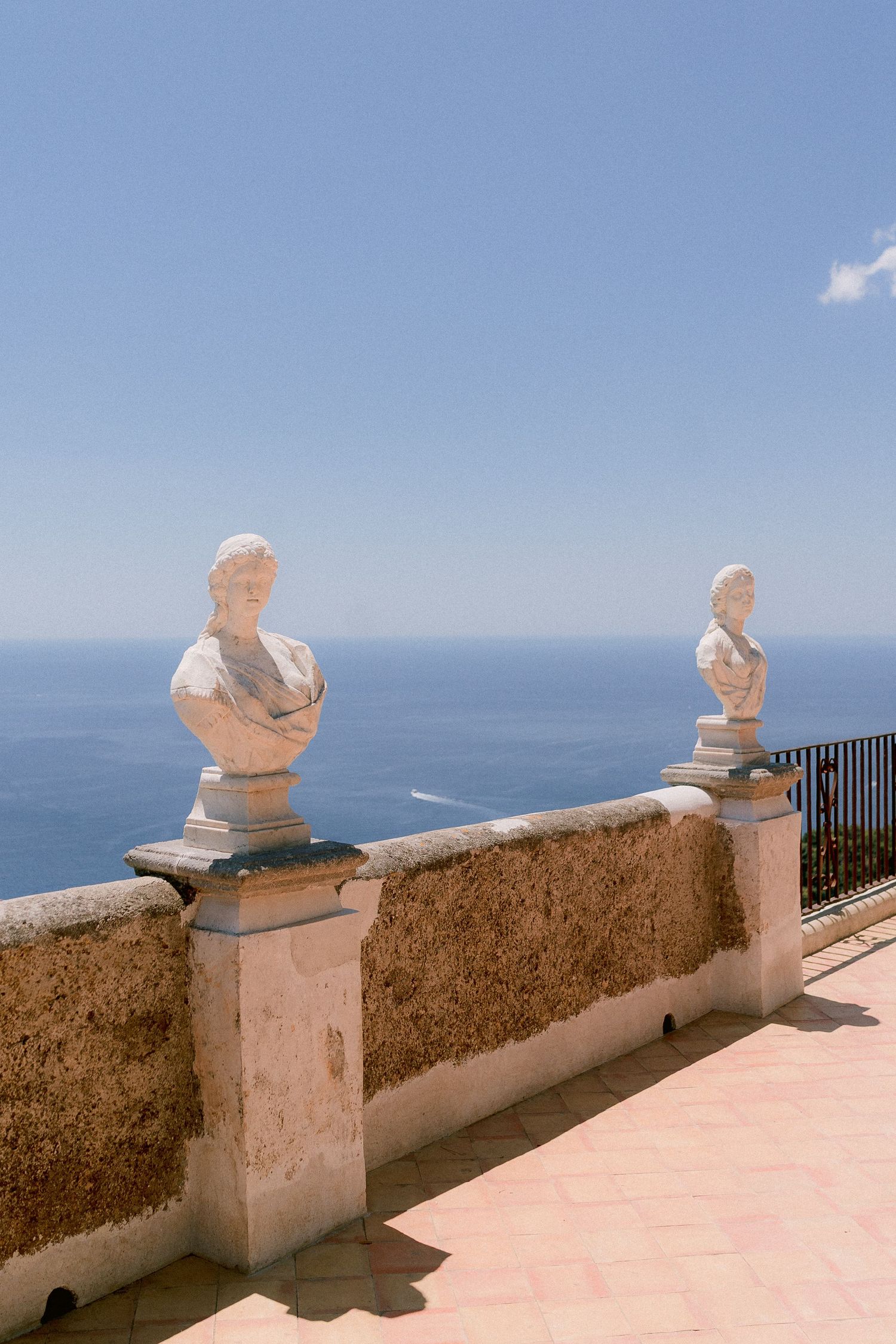 Two white marble busts on pedestals overlooking the Mediterranean Sea from a scenic terrazza dell'infinito in Ravello, Italy.