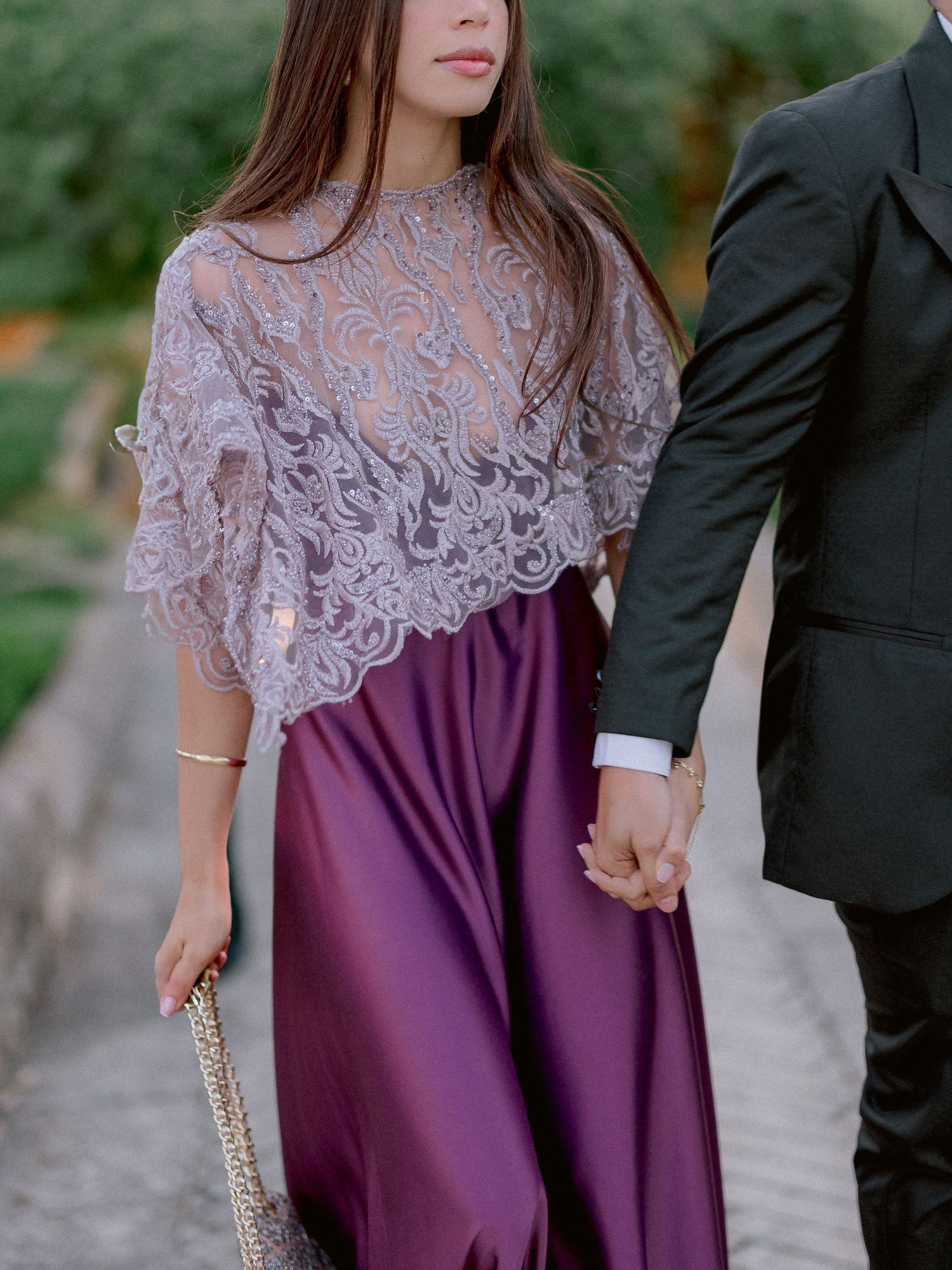 Elegant purple dress with grey lace overlay shawl and a sparkly clutch purse shown at an outdoor event.