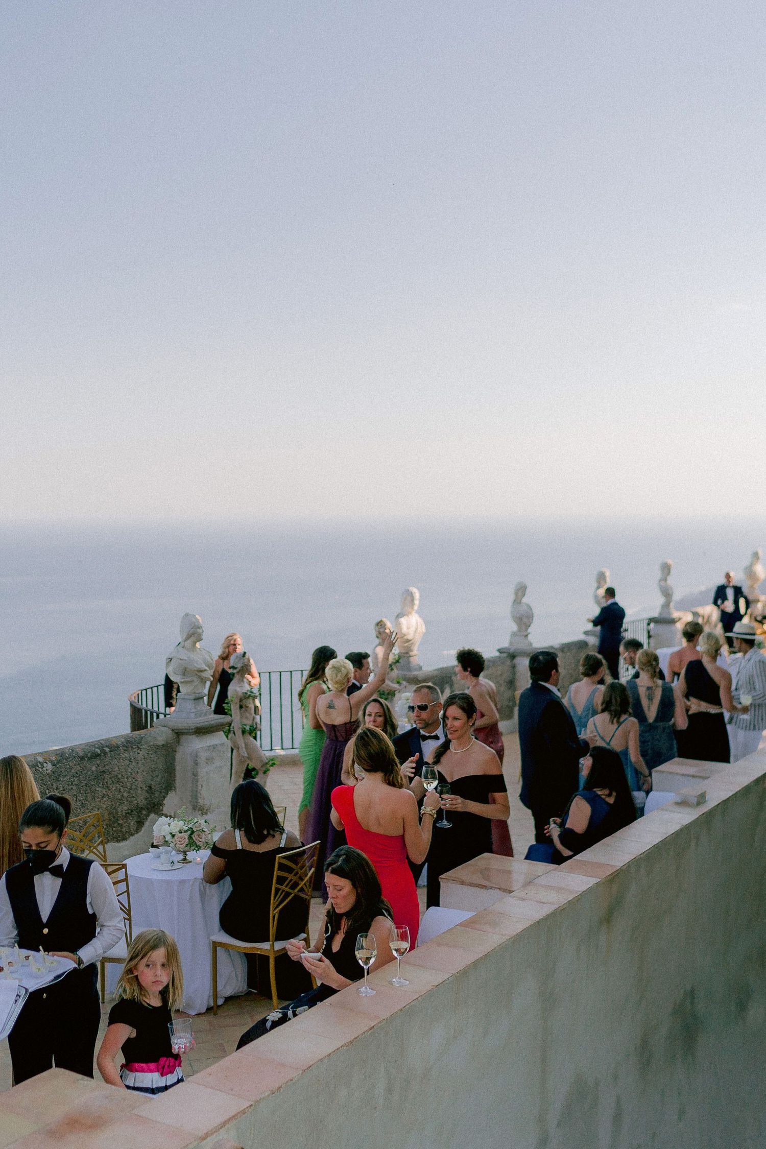 Wedding guests gather on a coastal terrazza dell'infinito overlooking the Mediterranean Sea during an elegant outdoor reception.