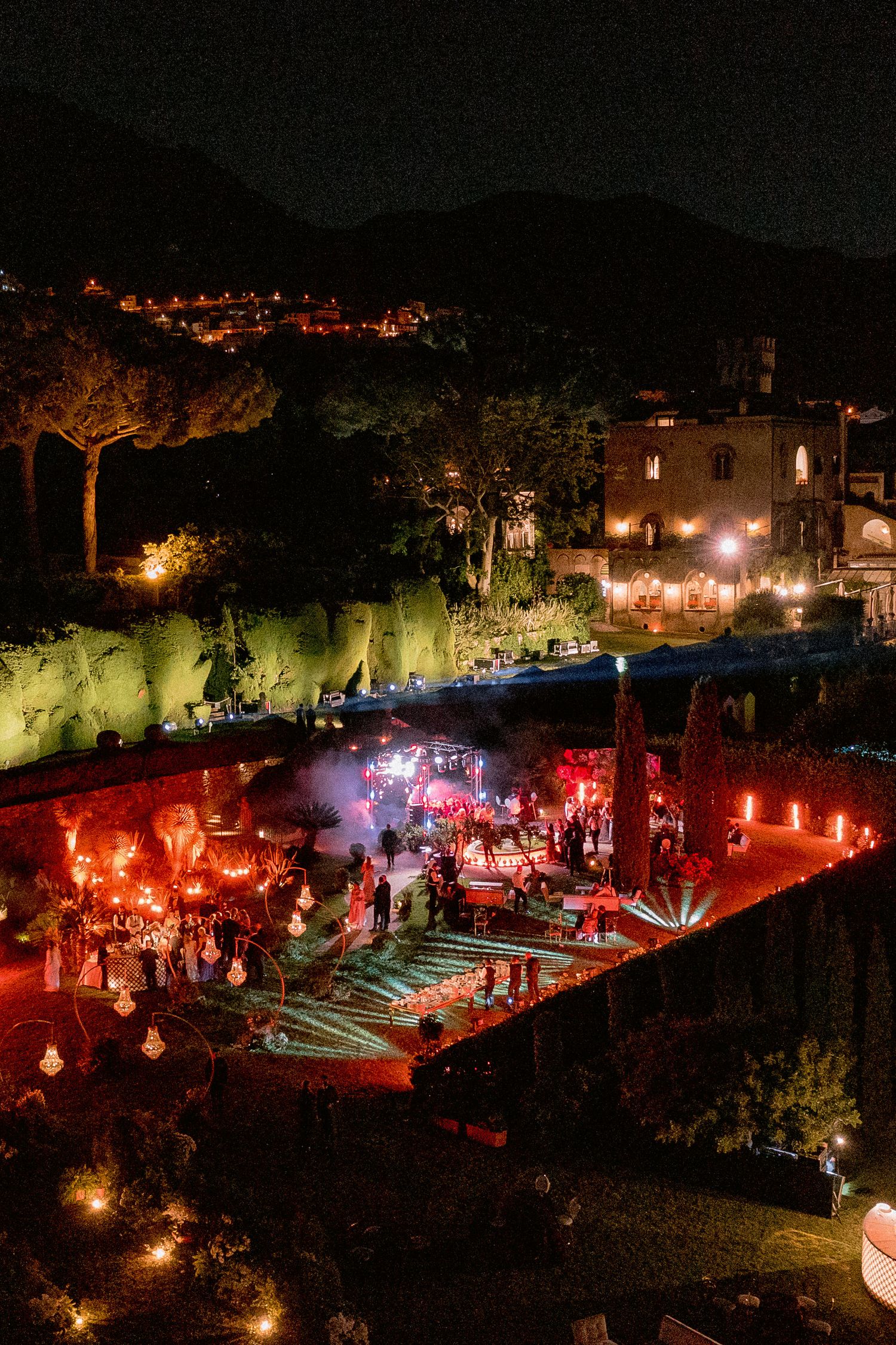 A nighttime Villa Cimbrone illuminated with dramatic red lighting and string lights in a historic hilltop setting.