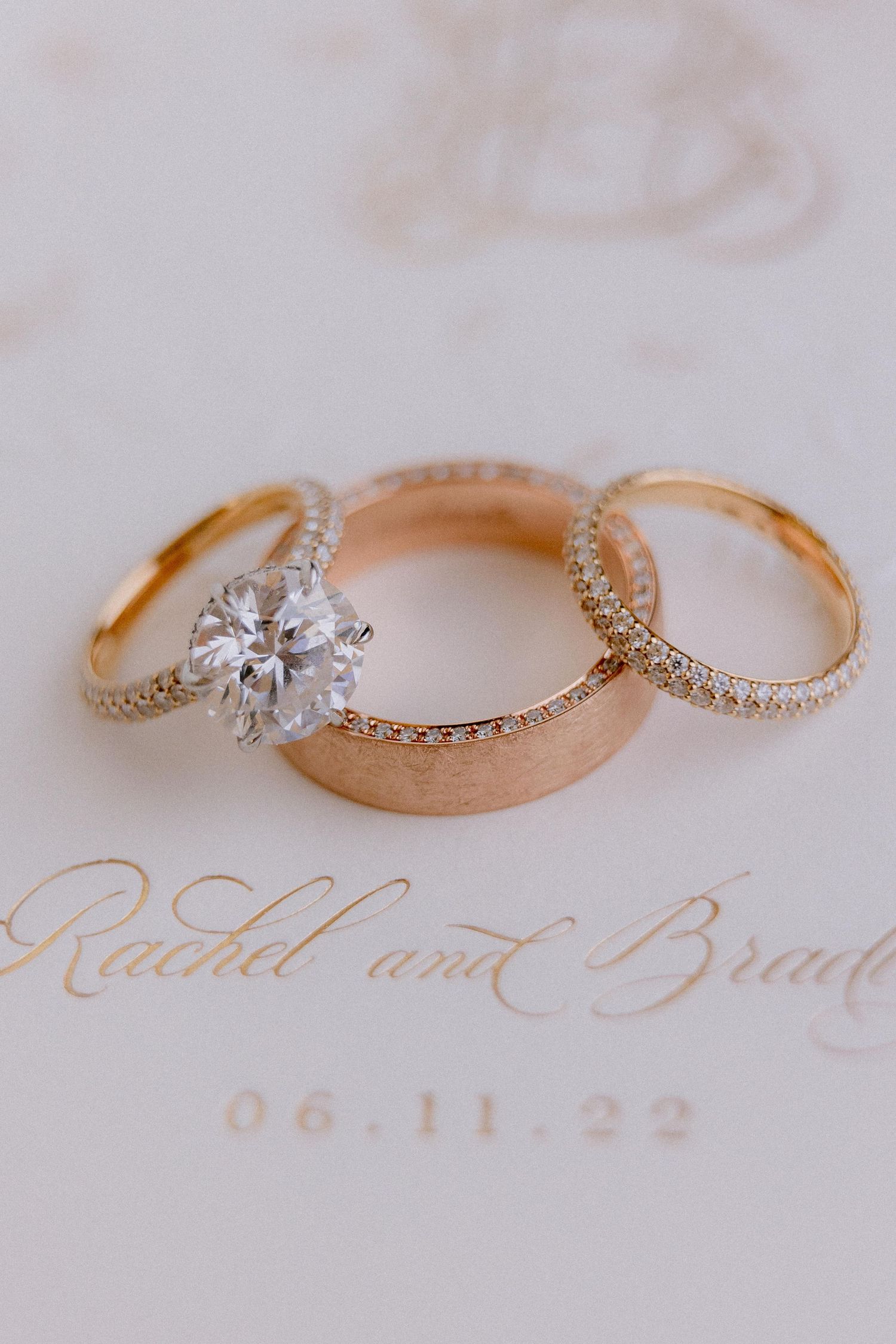 Three wedding rings including a diamond engagement ring and wedding bands resting on elegant calligraphy text.