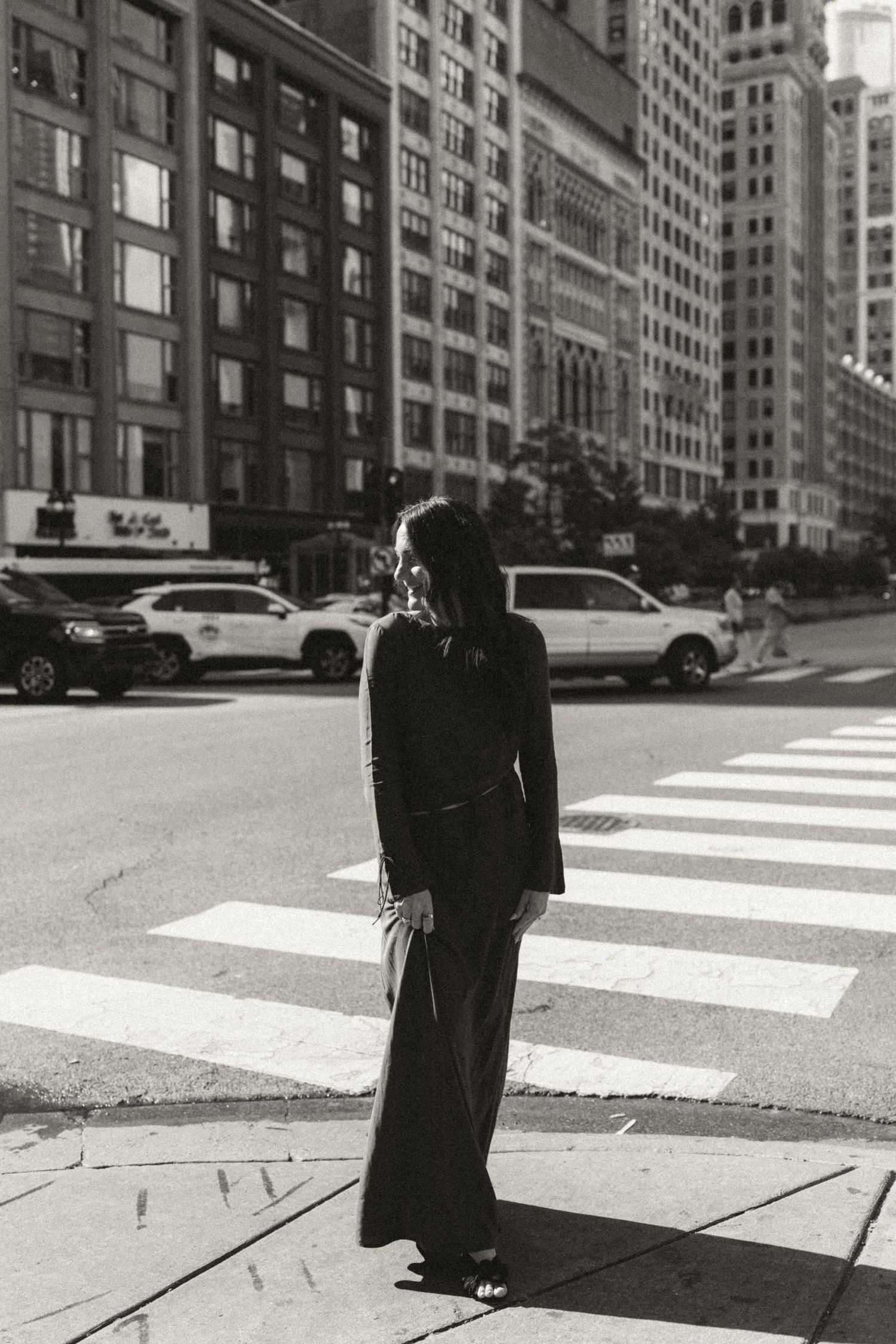 A black and white photo series shows a figure walking across a city crosswalk casting long shadows in dramatic light.