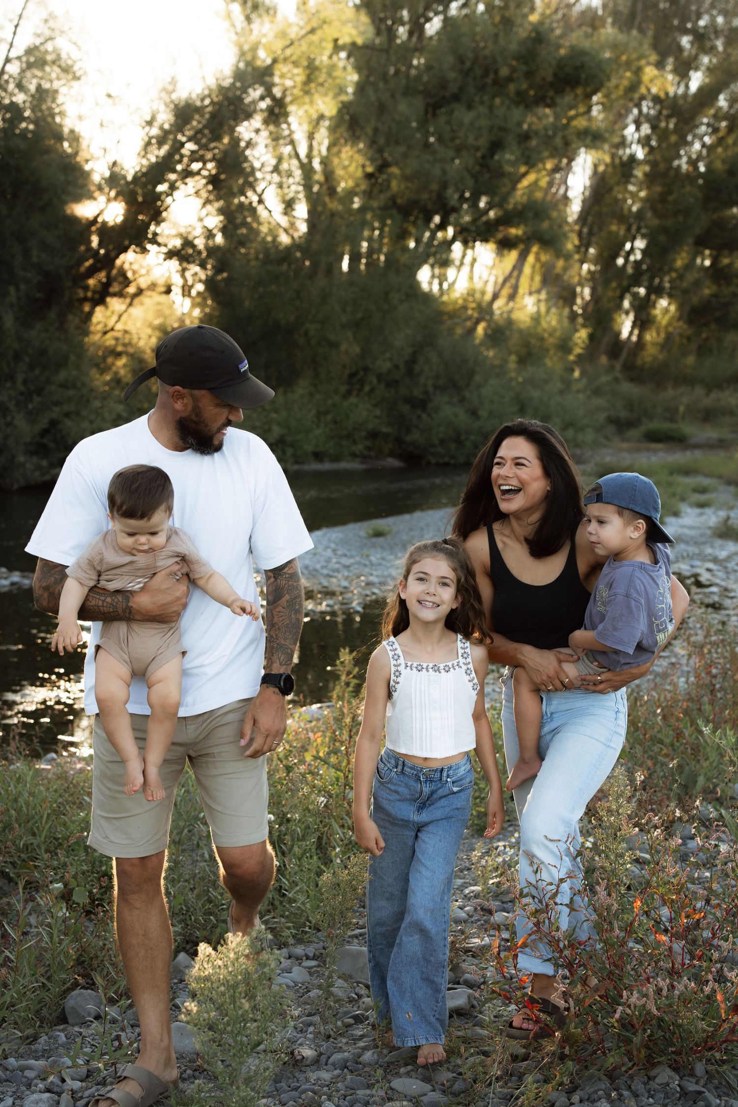 Happy family walking together among wildflowers during golden hour sunset.