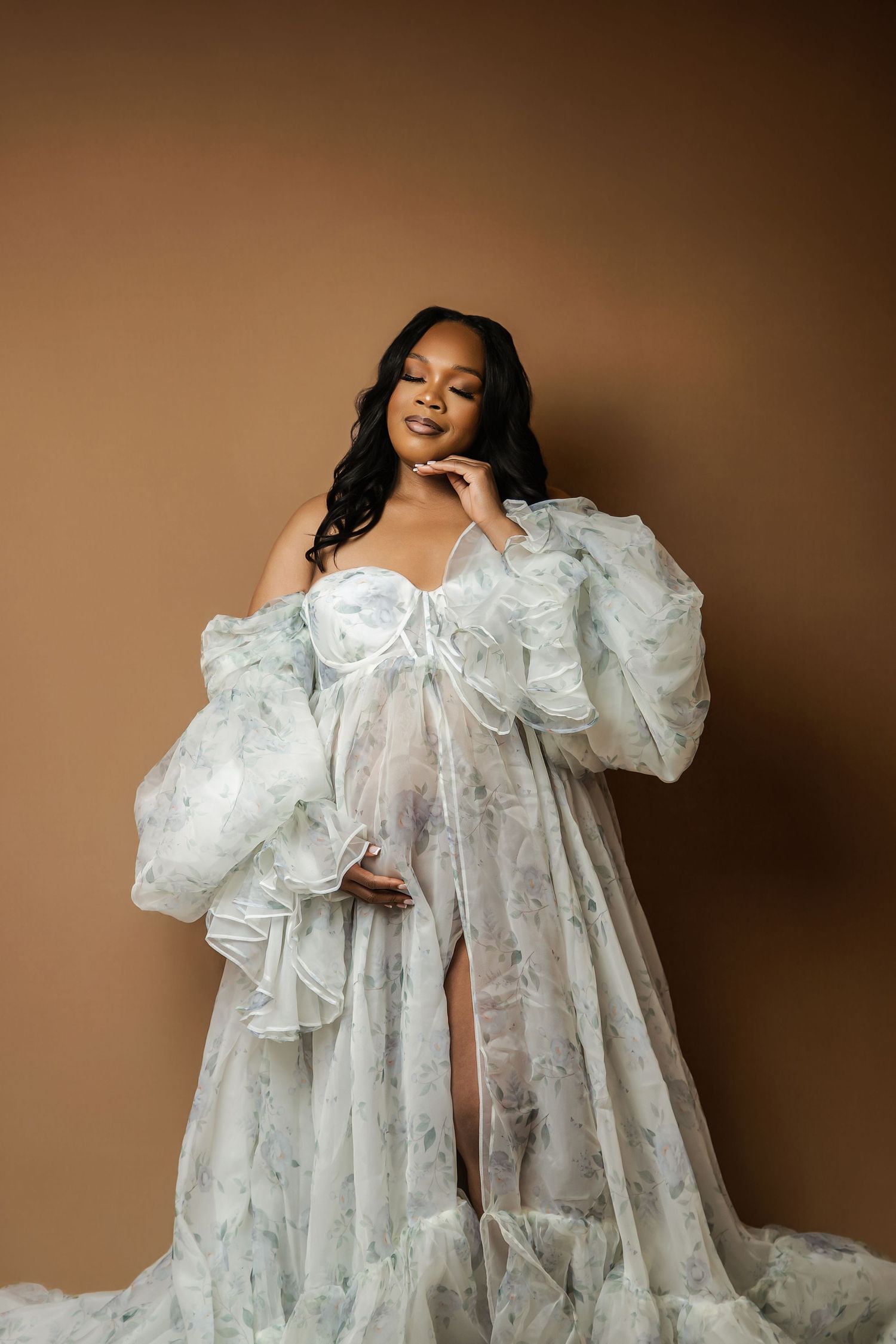 Elegant maternity boudoir photo in flowing white lace gown.