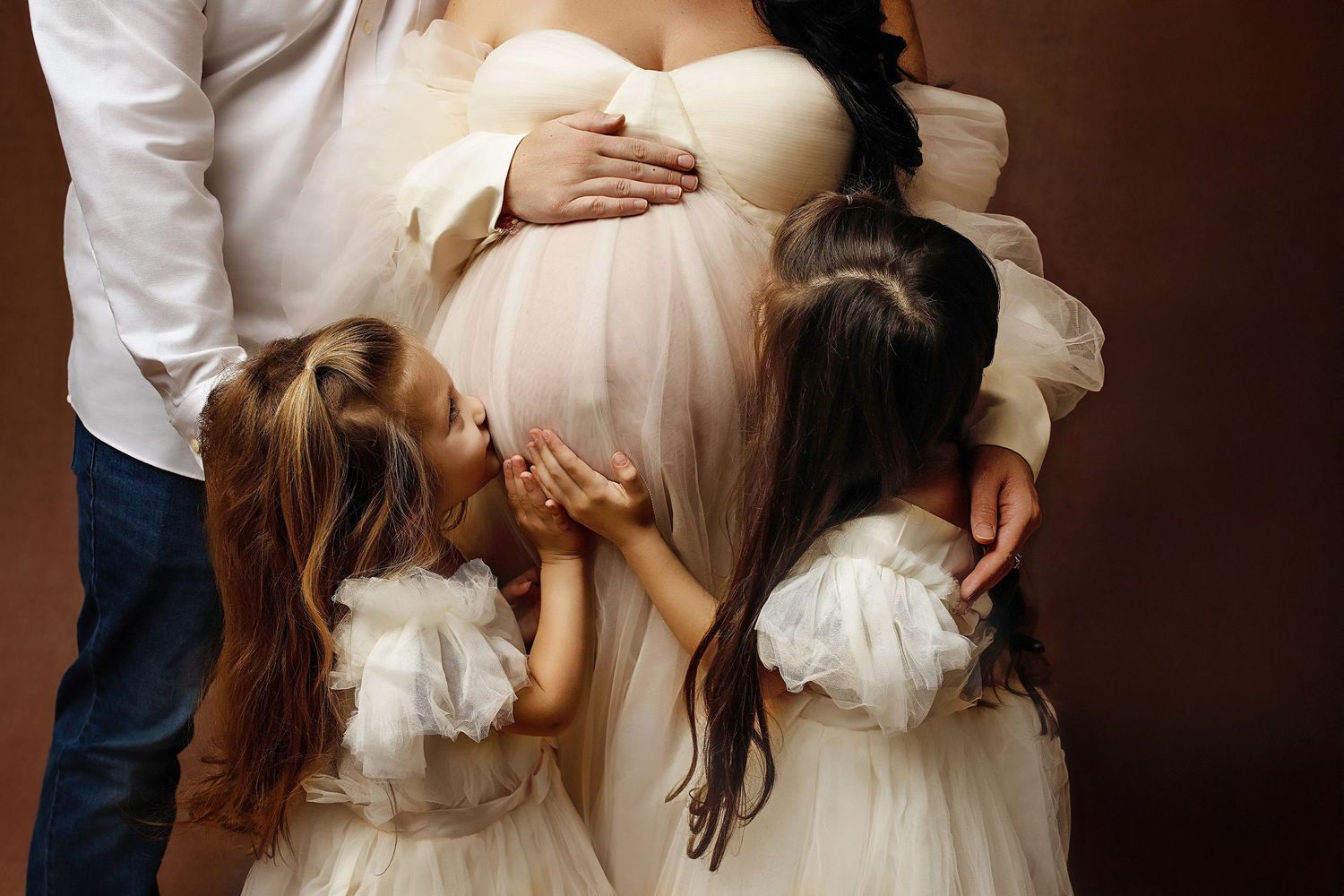 Touching family maternity photo with children embracing mother's pregnant belly.
