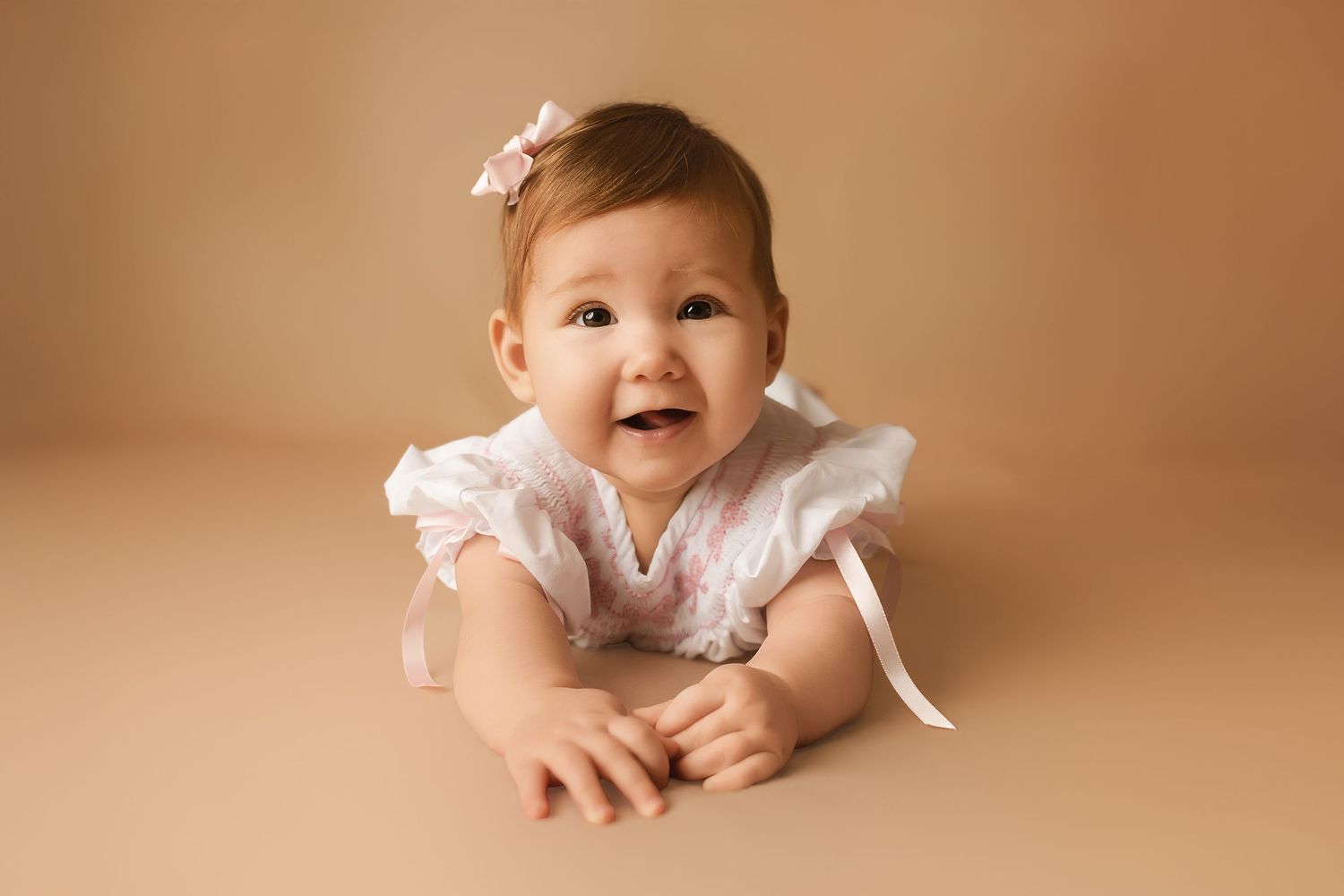 Artistic baby portraits against warm beige backdrop in studio setting.