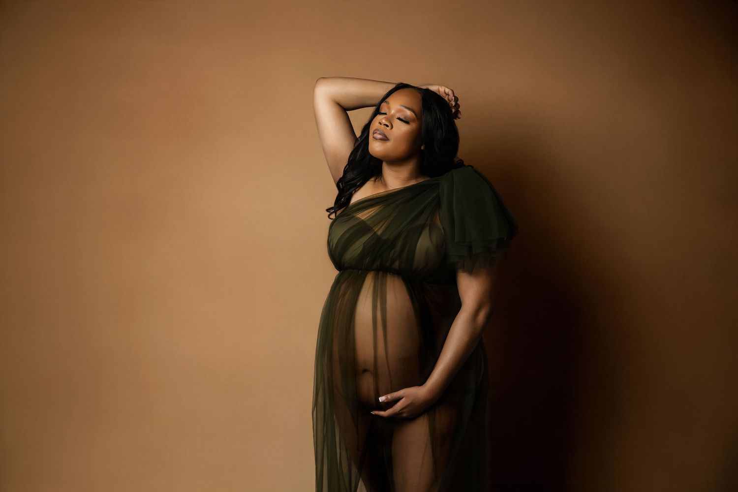 Studio maternity portraits with dramatic lighting and flowing fabric.