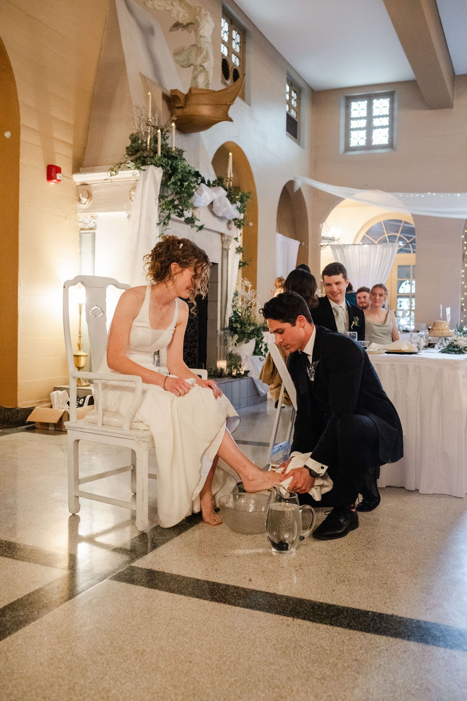 Wedding couple bending down on polished marble floor during reception in elegant church hall.