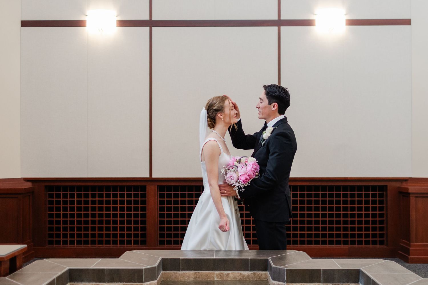 Wedding moment captured in modern church interior with dramatic lighting and wooden details.
