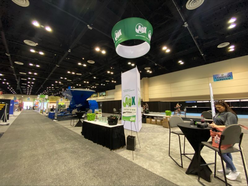 Trade show booth setup with large green cap display in a convention center.