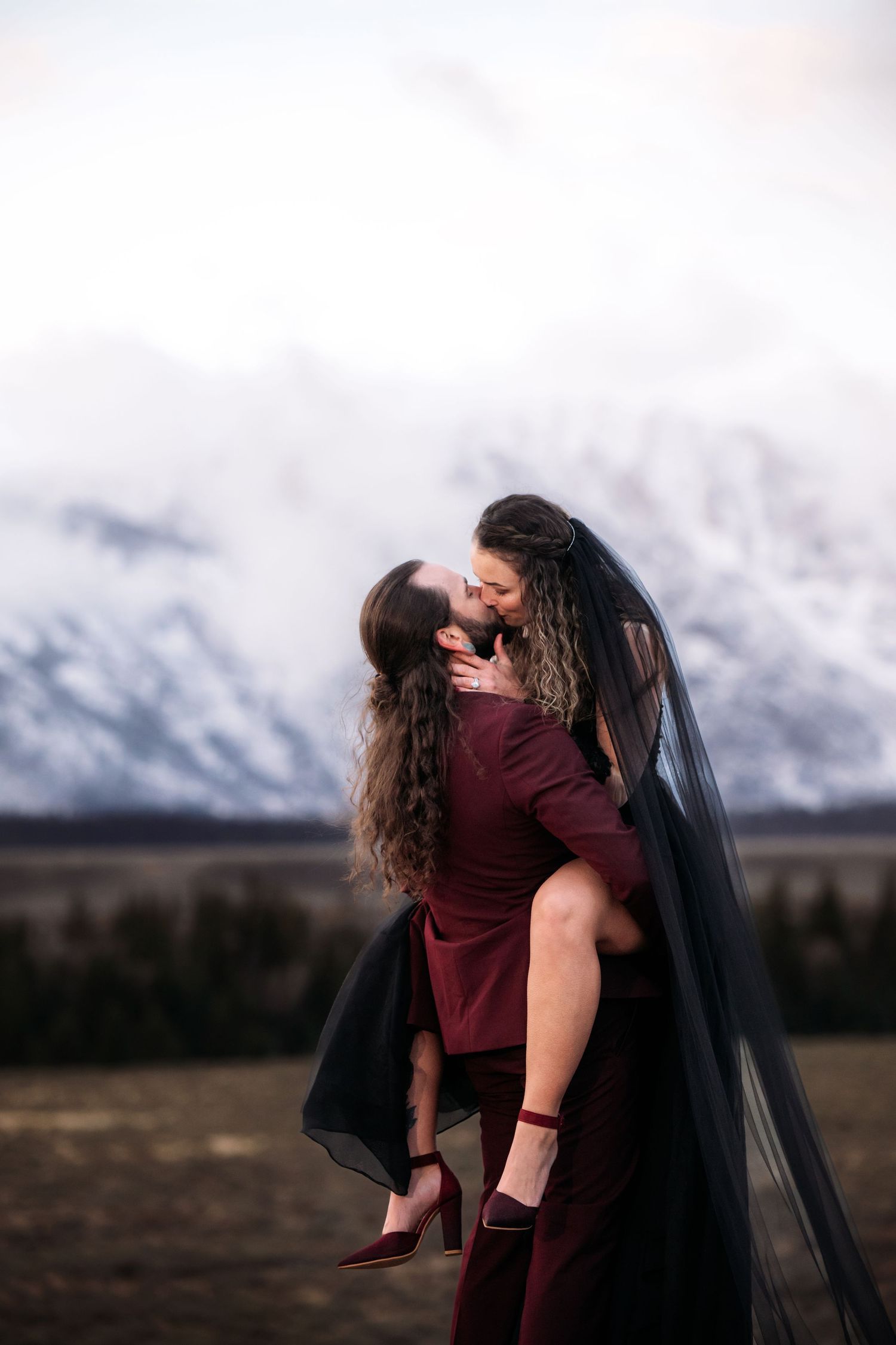 Two people embrace in a romantic dance pose against a backdrop of snowy mountains.