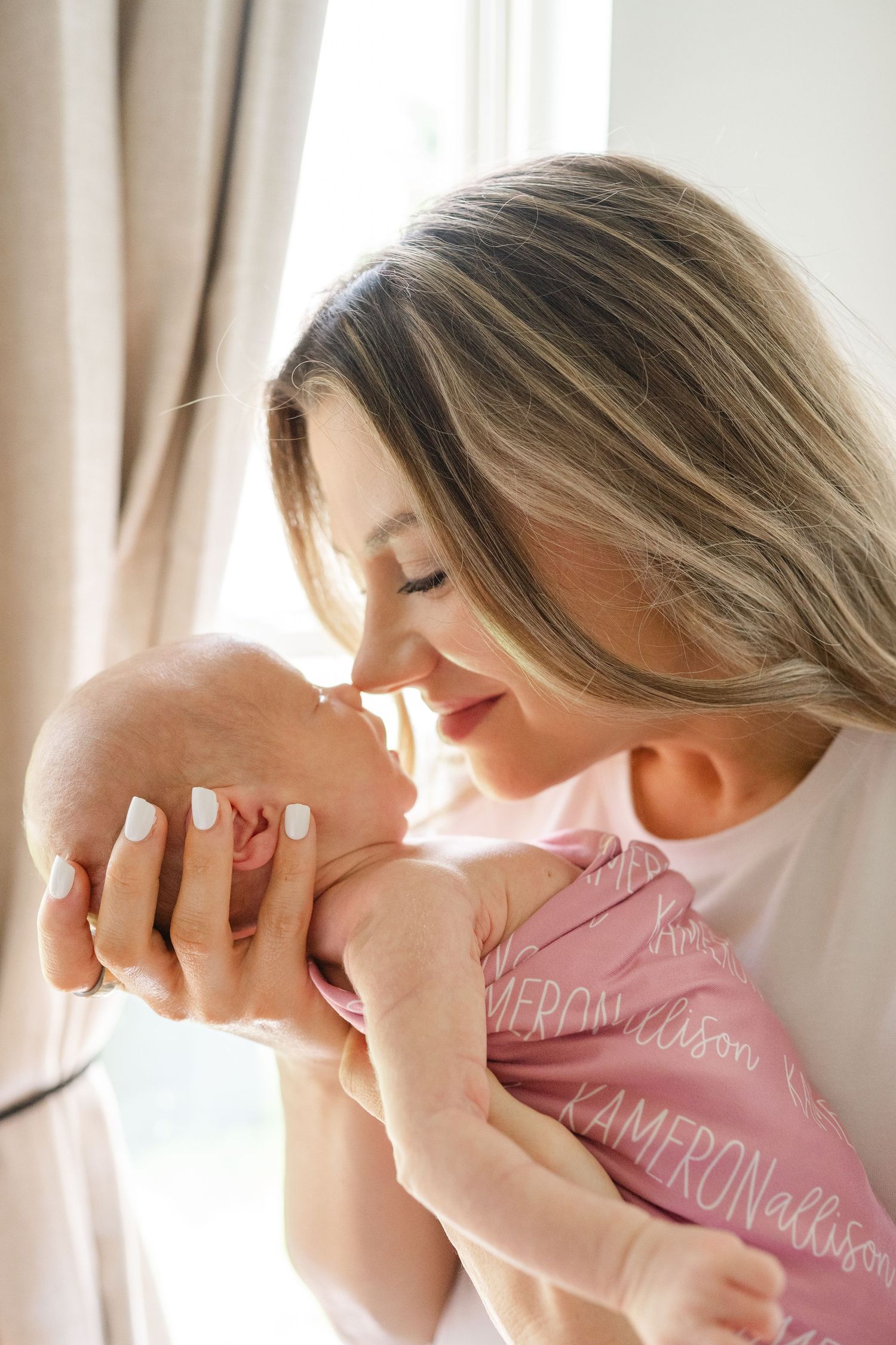 Mother holds nose to newborn baby's nose for newborn photography in Edmond, OK