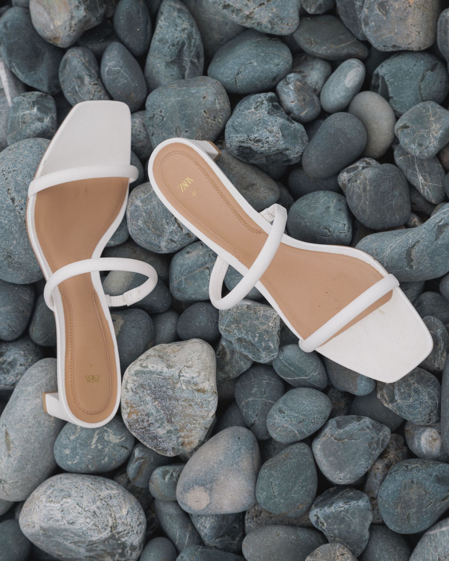 White wedding heels on the rocks of Torbay Beach in natural light, photographed by Newfoundland wedding photographer Kaitlyn Yvette.
