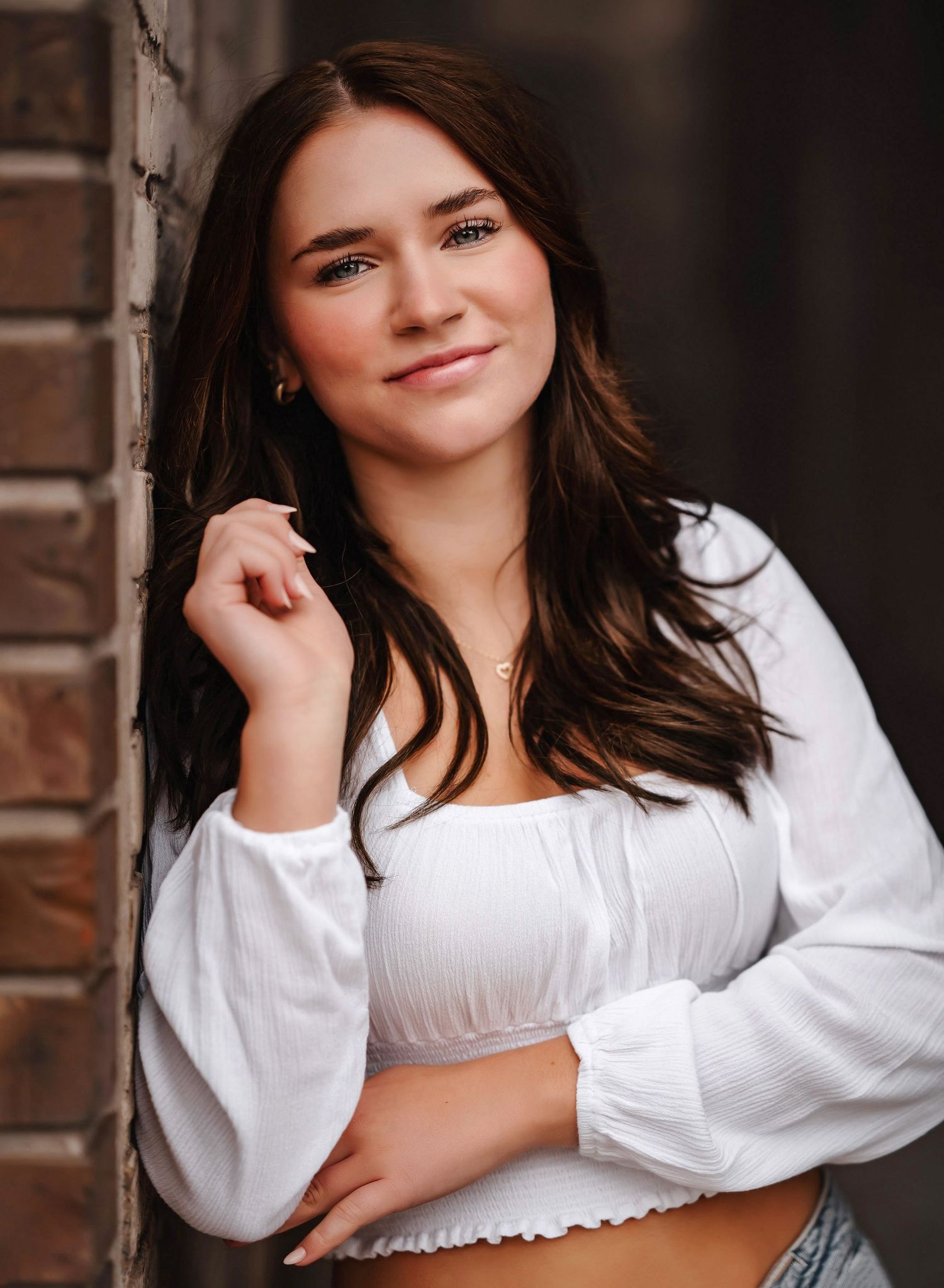 Portrait series featuring someone in a white peasant top against a brick wall background.