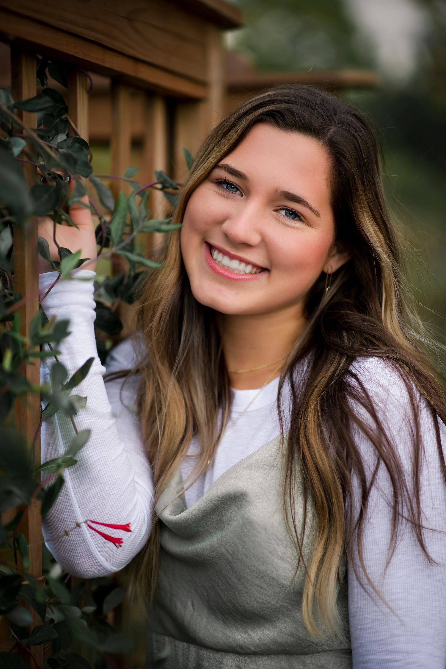 Candid outdoor portrait series showing someone in a white sweater and gray vest among foliage.