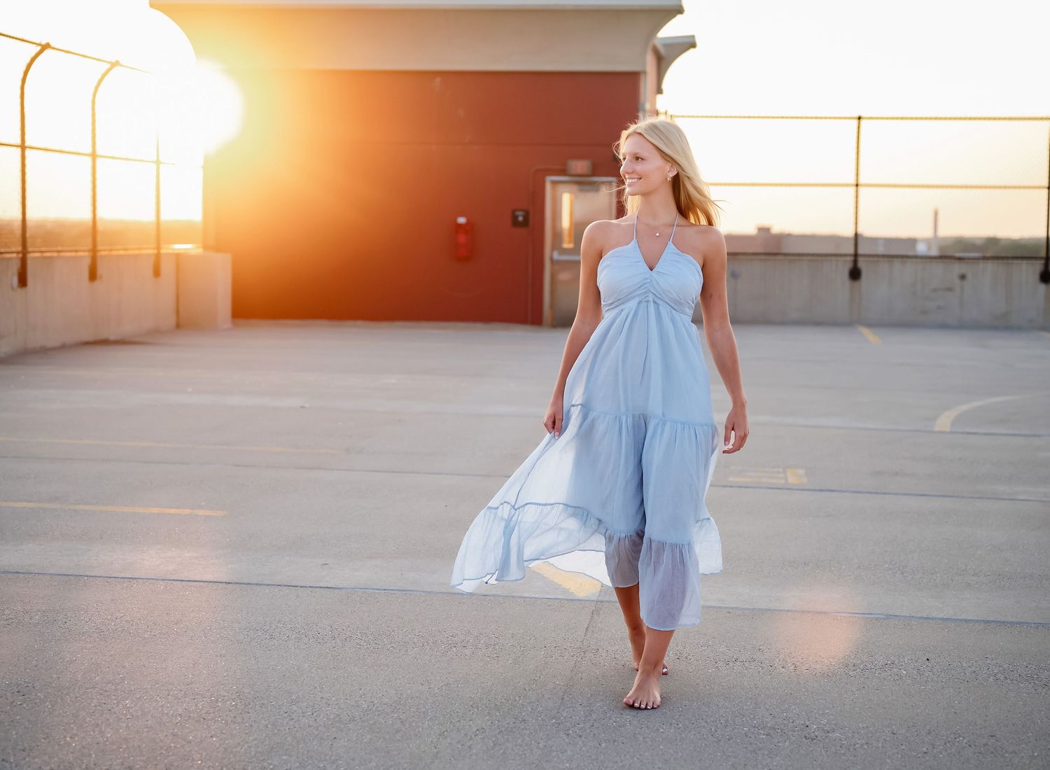Sunset photoshoot on rooftop wearing flowing blue dress with golden hour lighting.
