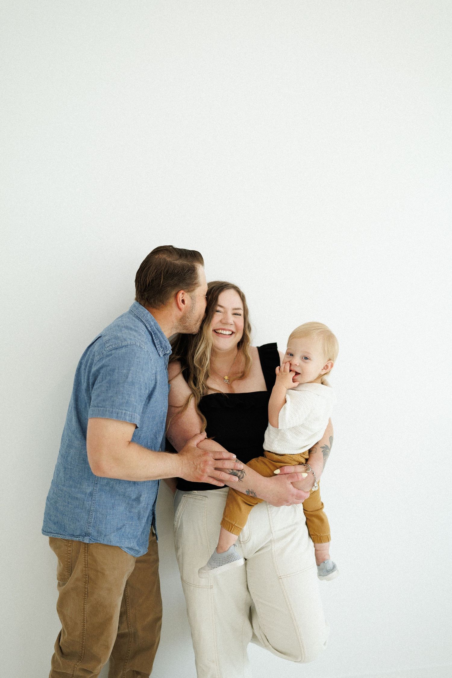 Happy family sharing a joyful moment together against a white wall.