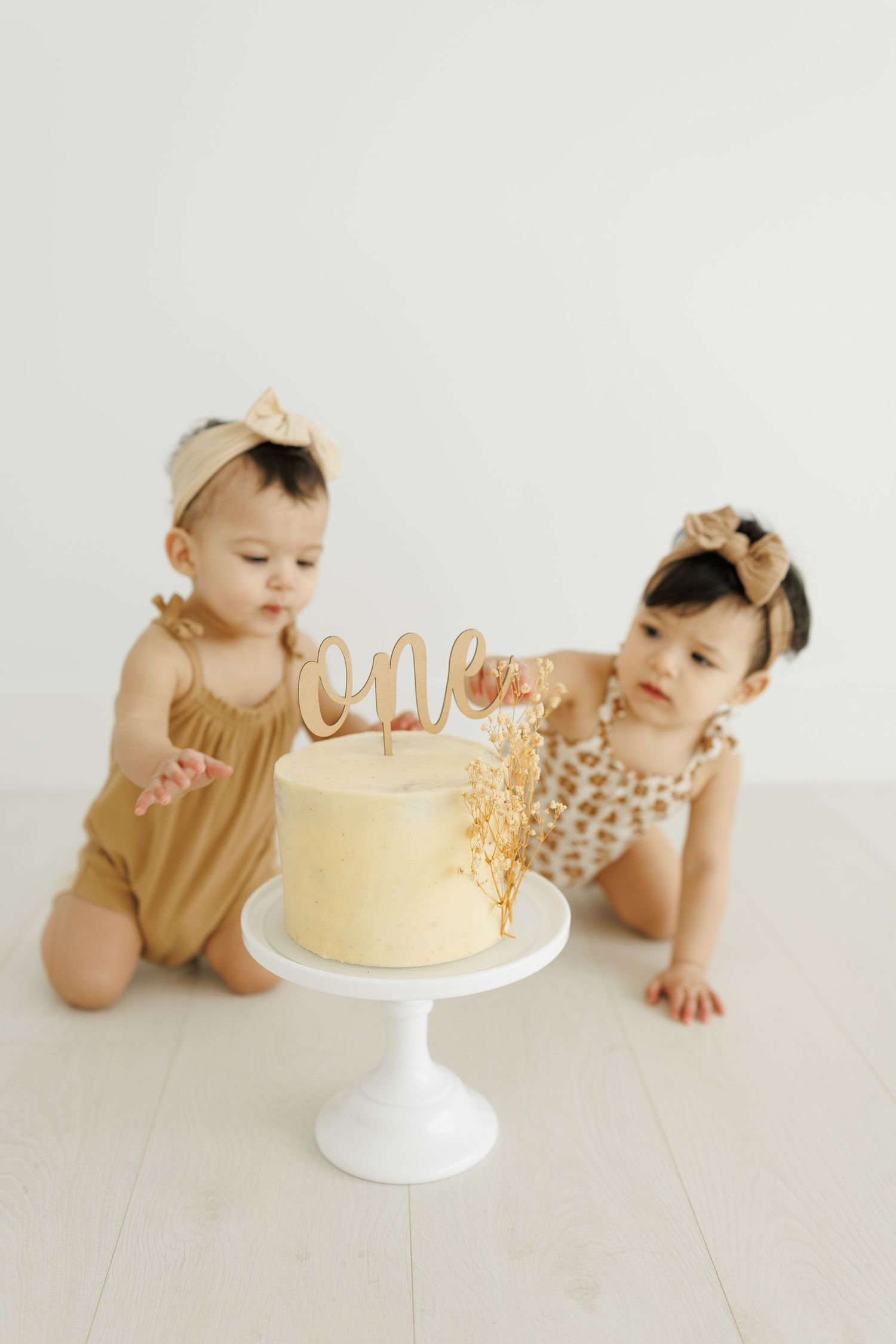 Simple yellow birthday cake on white pedestal stand decorated with gold topper and sprinkles.