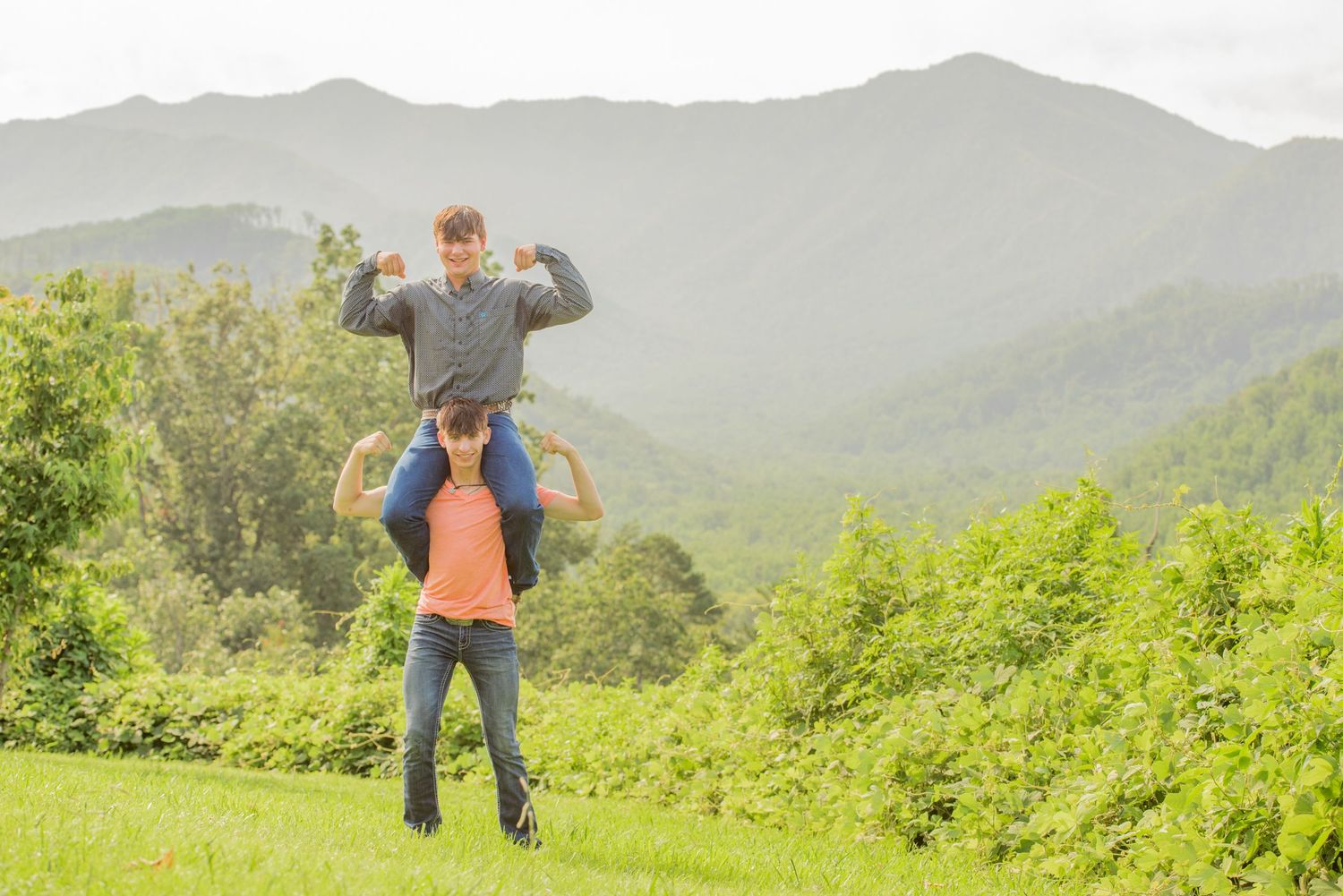Pigeon Forge Photographers portrait of two brothers playing and having fun outdoors against a backdrop of misty mountain peaks.