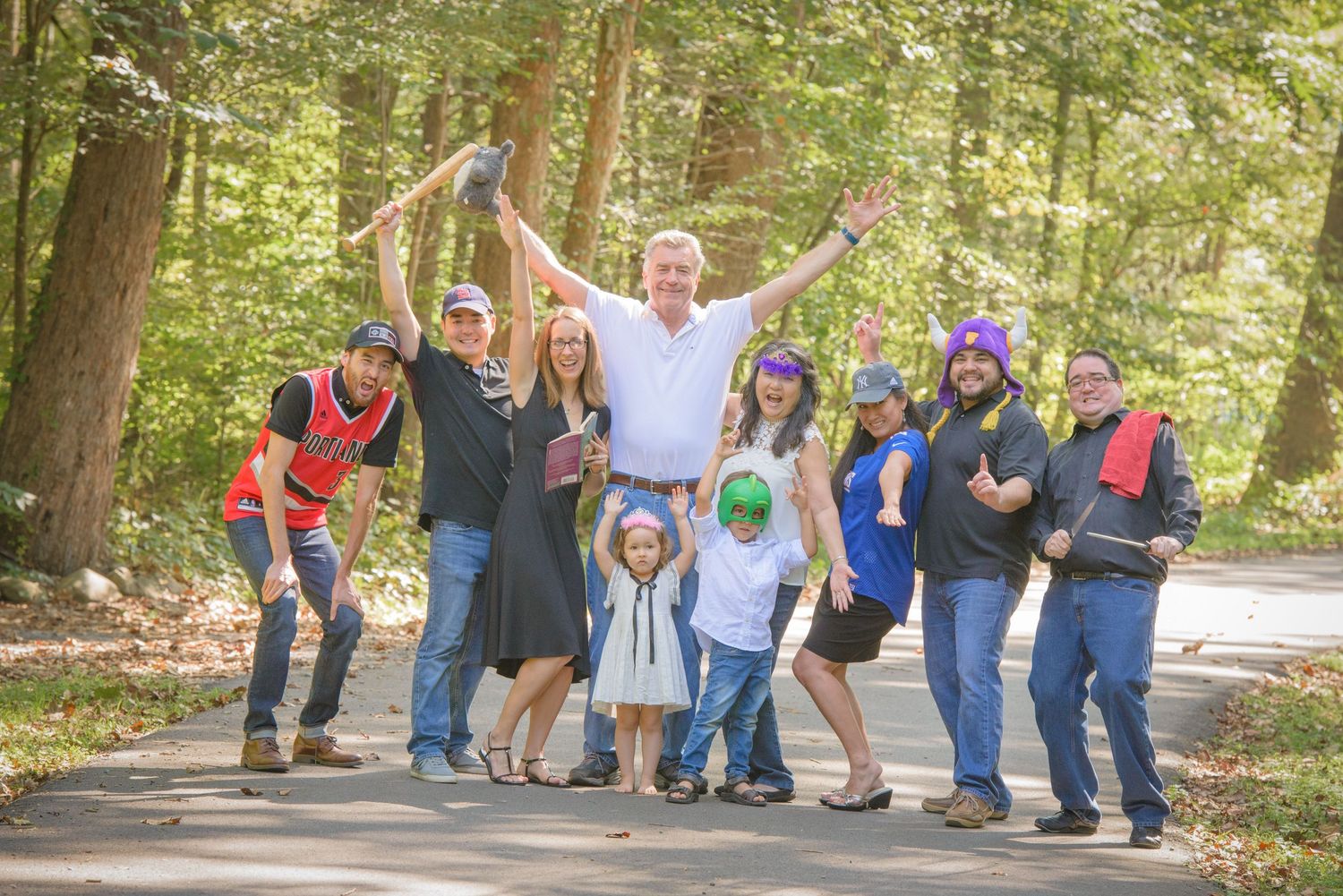 Pigeon Forge TN Photographer portrait of a cheerful family poses together on a wooded path with raised arms and playful expressions.