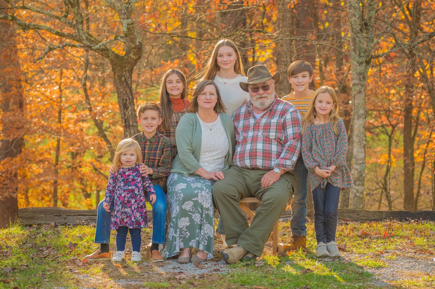 A family poses together outdoors against vibrant autumn foliage with golden leaves in the background in Gatlinburg TN.