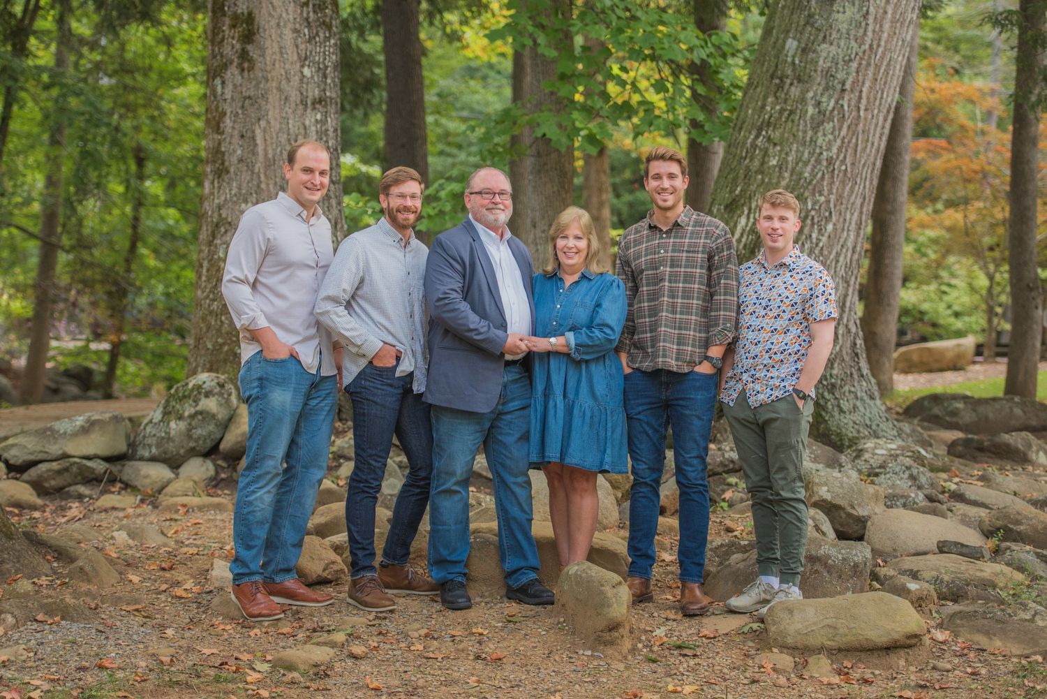 A family standing together outdoors in casual attire among autumn trees and rocks by Gatlinburg Photographer TN.