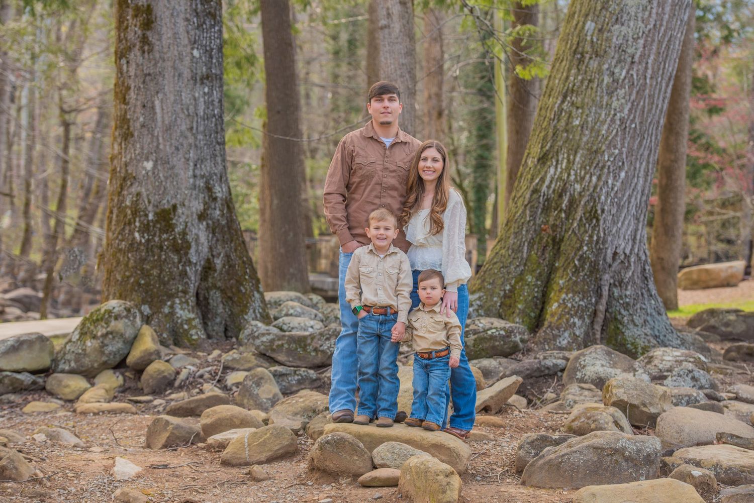 Gatlinburg Photographers portraits of a family standing together on rocky terrain in a scenic wooded forest setting'