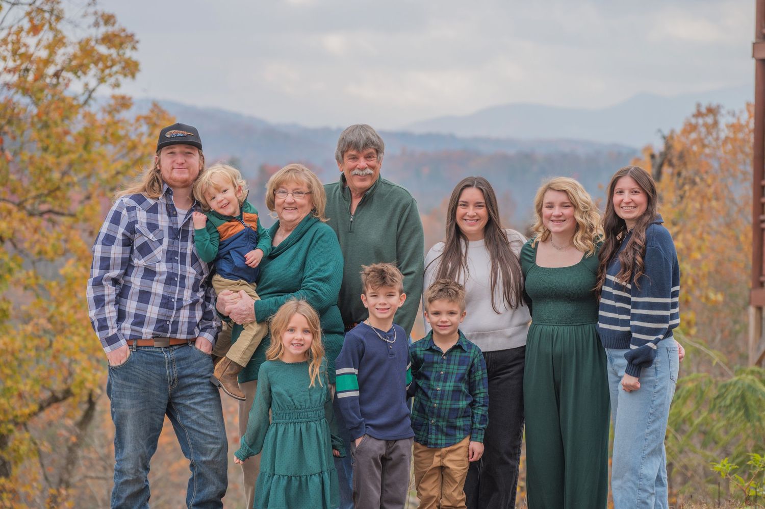 A group stands together outdoors against the Great Smoky Mountains with fall foliage in warm golden colors in Sevierville TN.