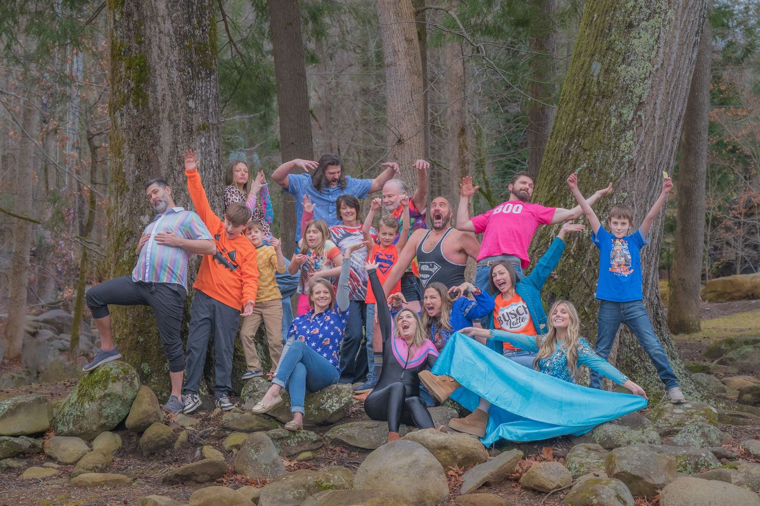 A cheerful family poses together on rocky terrain in a wooded forest area while wearing colorful outdoor clothing in Pigeon Forge tn.