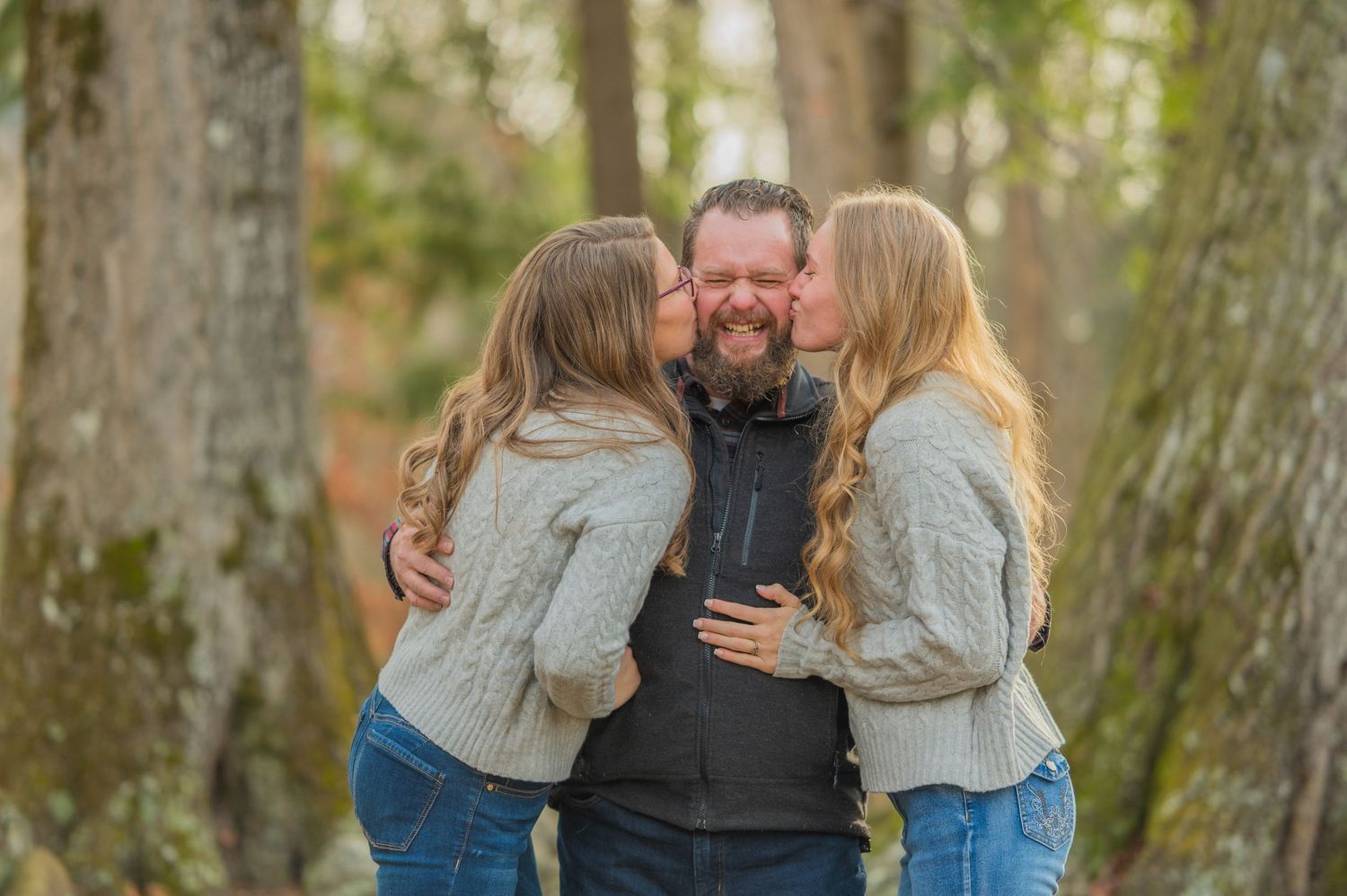 A family embraces warmly in a forest setting on an autumn day wearing cozy sweaters and jeans by Townsend TN Photographers.
