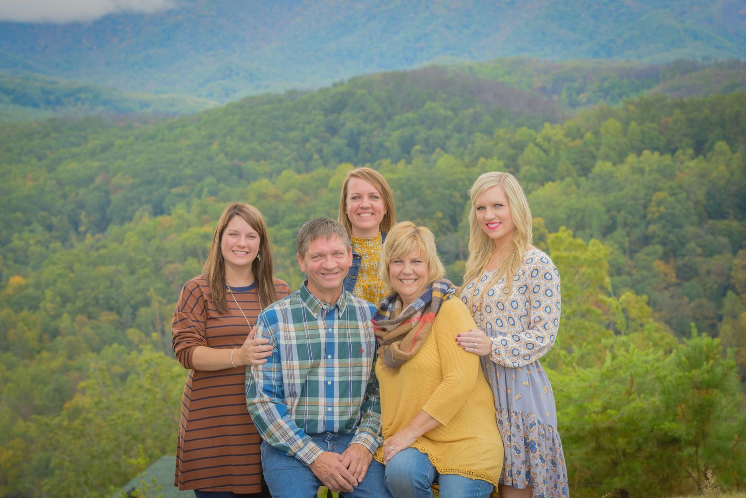 Pigeon Forge Photographer portrait of a family together on a hilltop overlook with lush green mountains in the background.