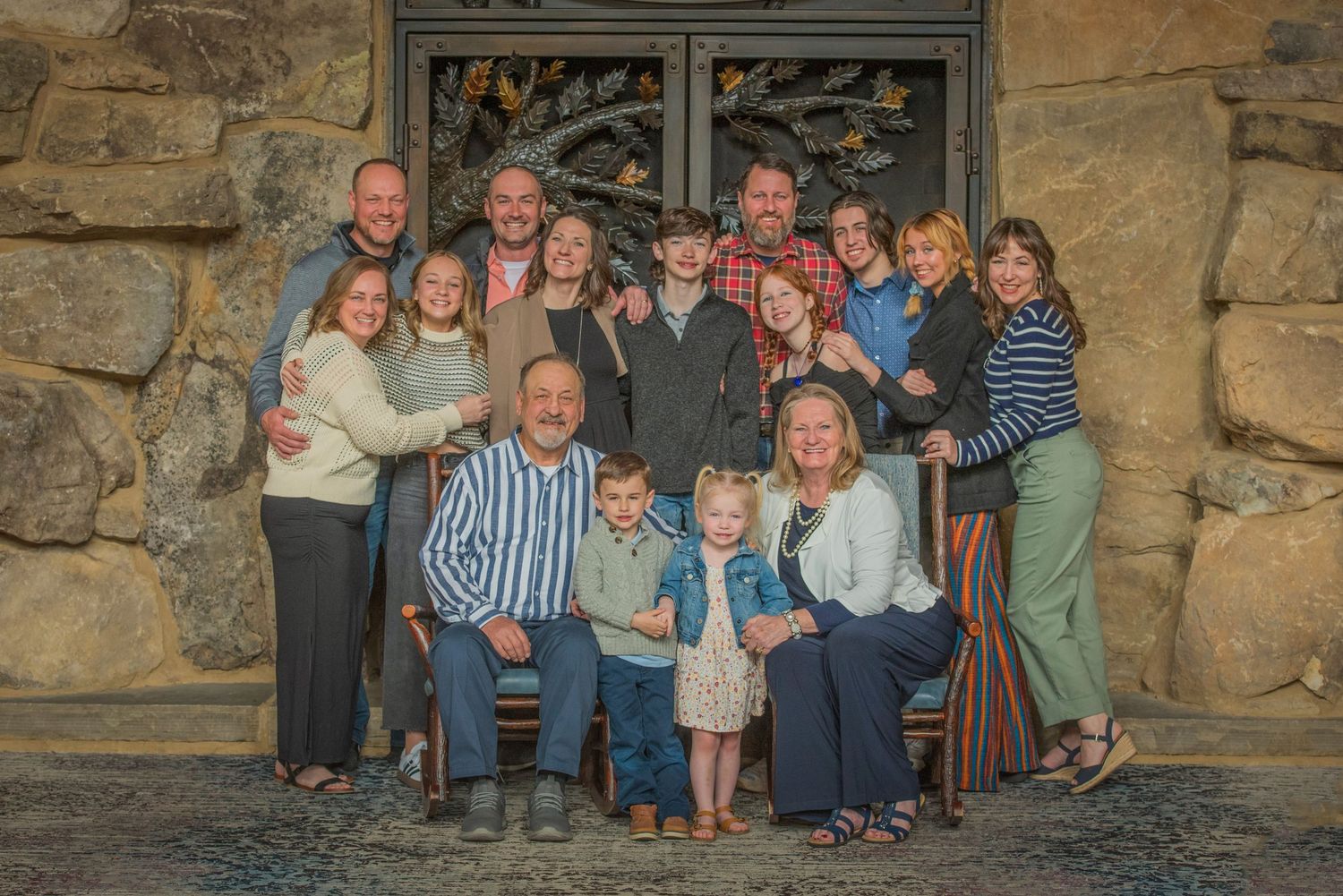 A large multi-generational family group poses together outside a rustic stone building entrance at Dollywood's HeartSong Lodge & Resort.