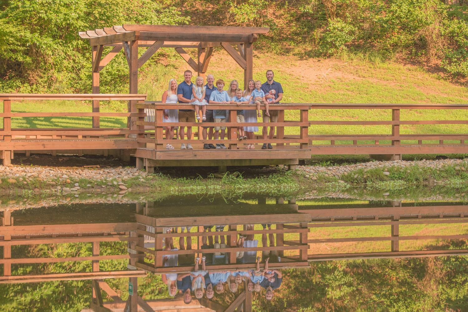 Family in matching blue shirts sitting on a wooden dock over calm water creating a perfect reflection in Sevierville TN.