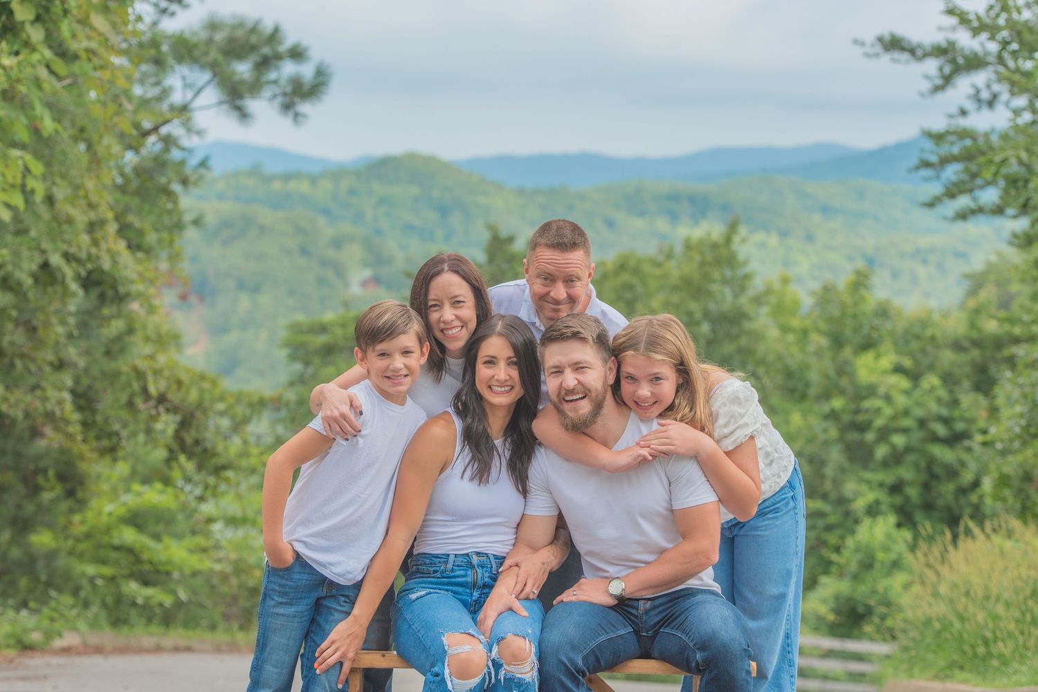 A joyful family together outdoors against a scenic mountain backdrop with green trees and rolling hills at a cabin rental in Sevierville tn.