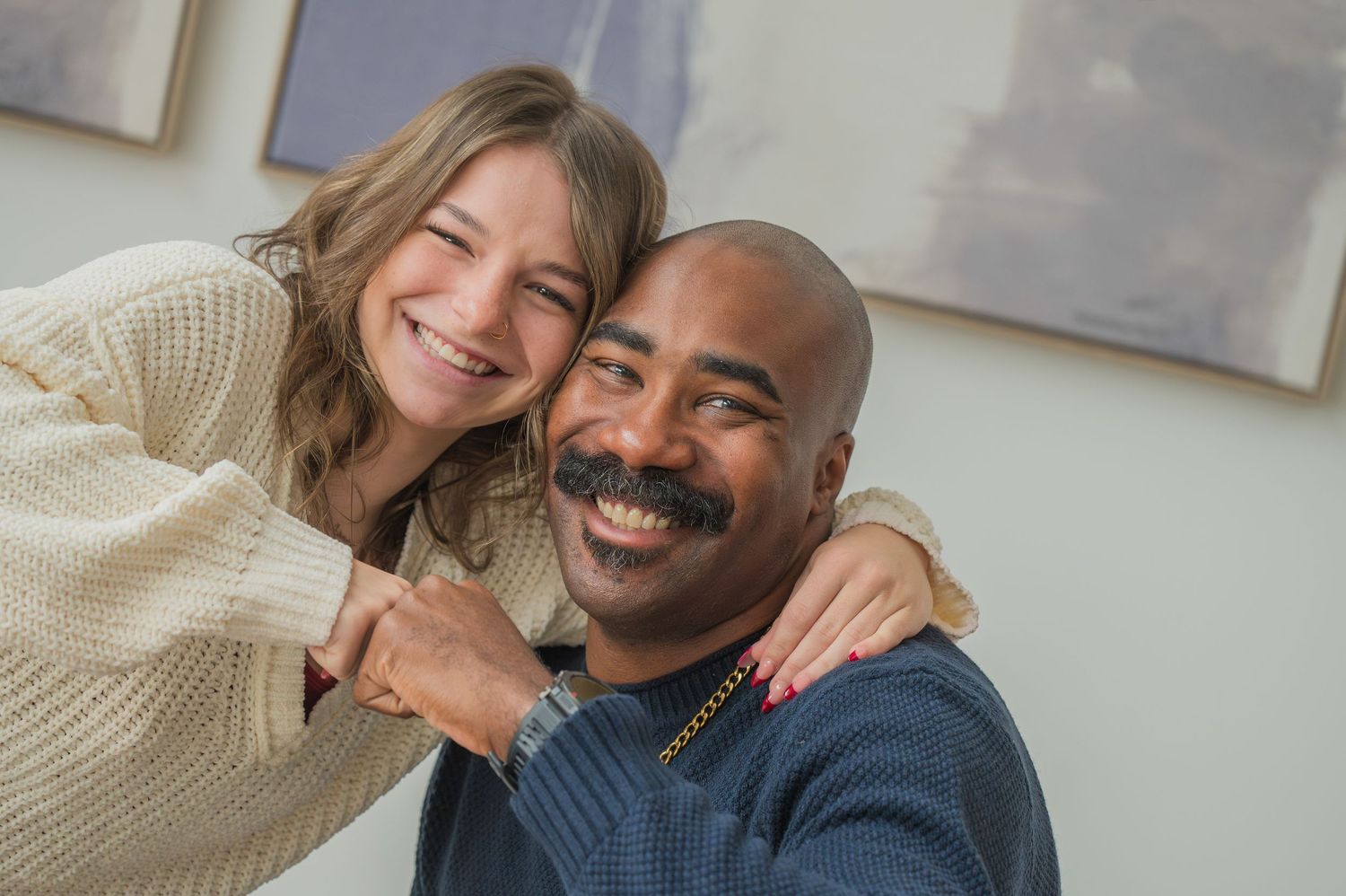A joyful couple in sweaters share a warm embrace while laughing together indoors in Gatlinburg TN.