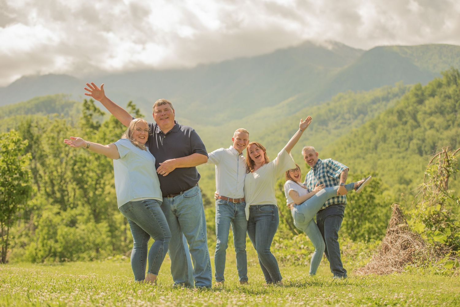 gatlinburg tn photographers portrait of a family celebrates joyfully while posing outdoors in a scenic mountain landscape.