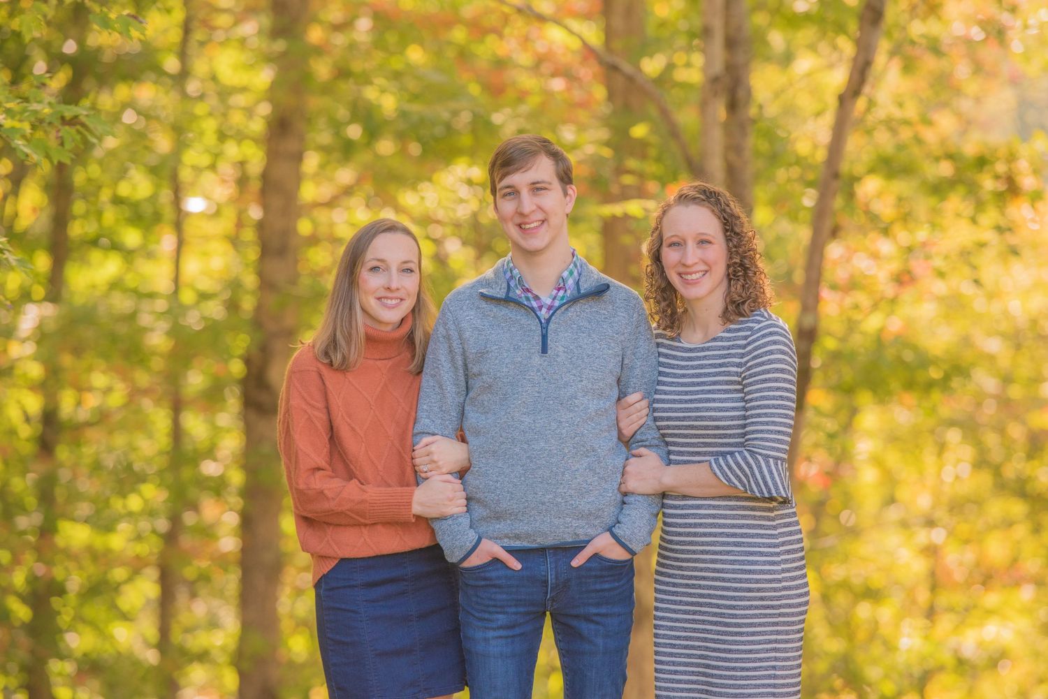 Bother and sisters smiling together outdoors with autumn foliage in the background during golden hour at their rental in Gatlinburg TN.