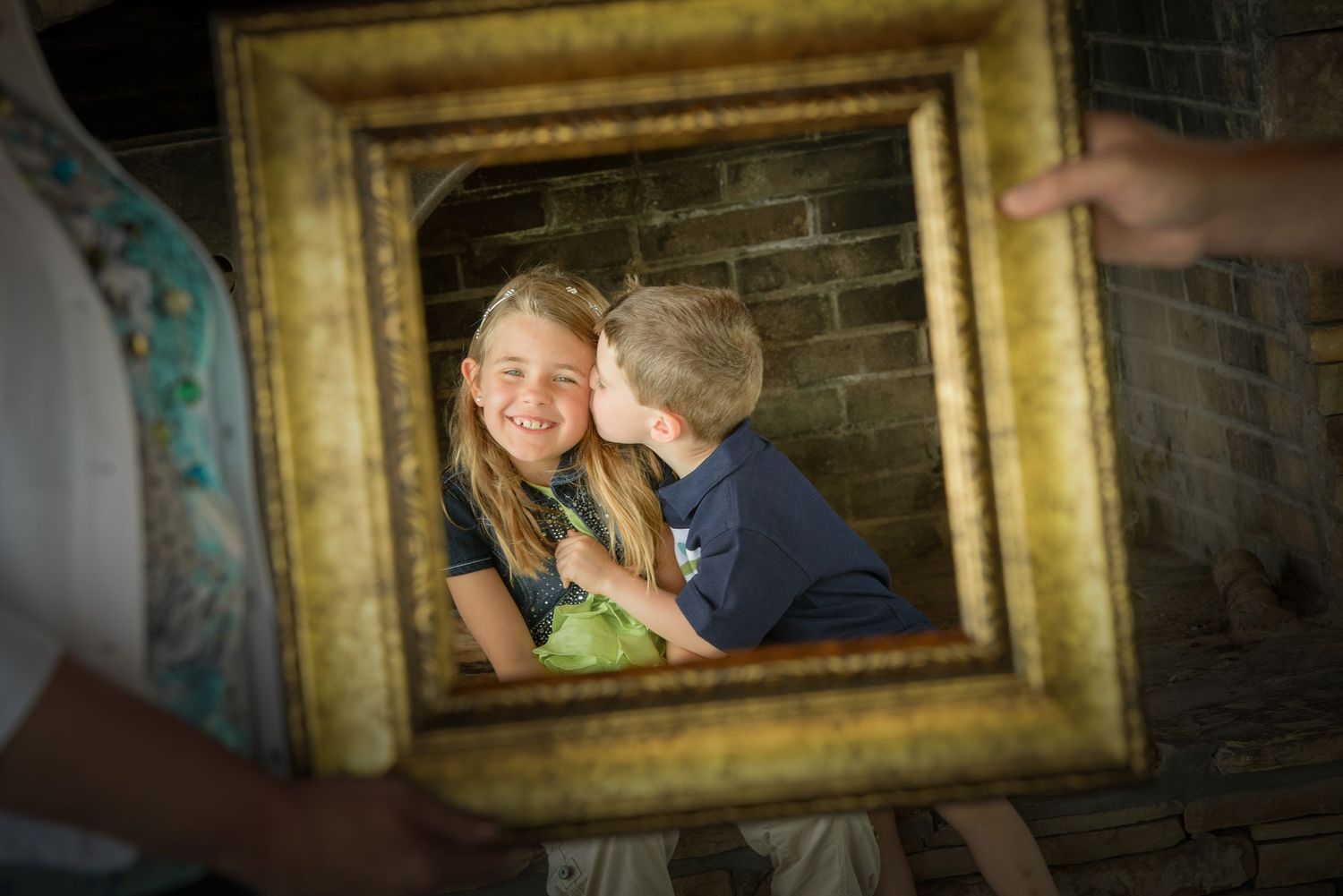 A tender moment captured through an ornate gold frame against a brick wall background in Gatlinburg TN.