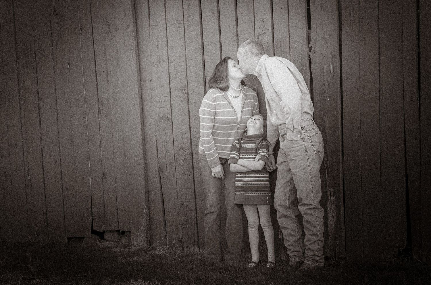 A touching black and white family portrait against a barn by Pigeon Forge Photographers.
