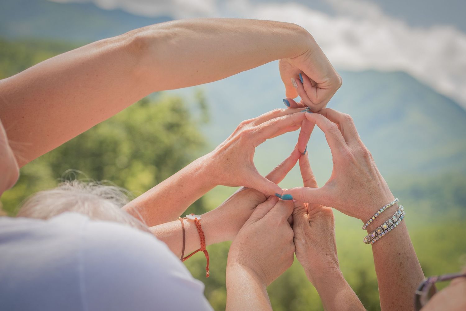 Hands come together to form a peace sign symbol against a blurred green mountain landscape background at the Great Smoky Mountains.