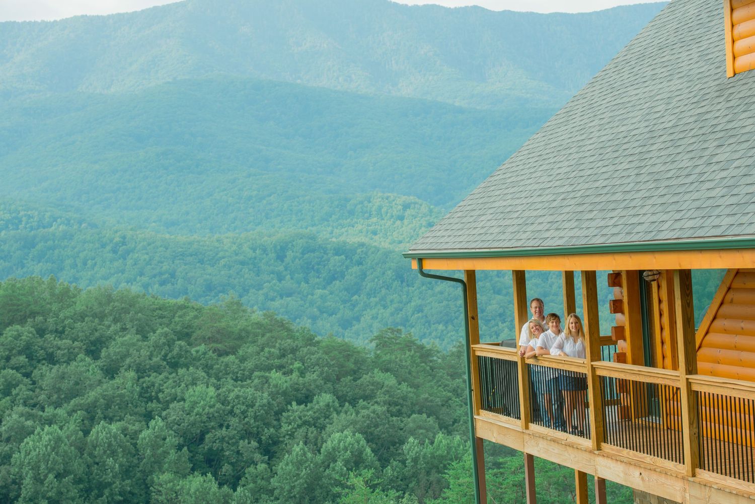 A log cabin deck overlooks a stunning vista of rolling mountains and dense forest in the Great Smoky Mountains.