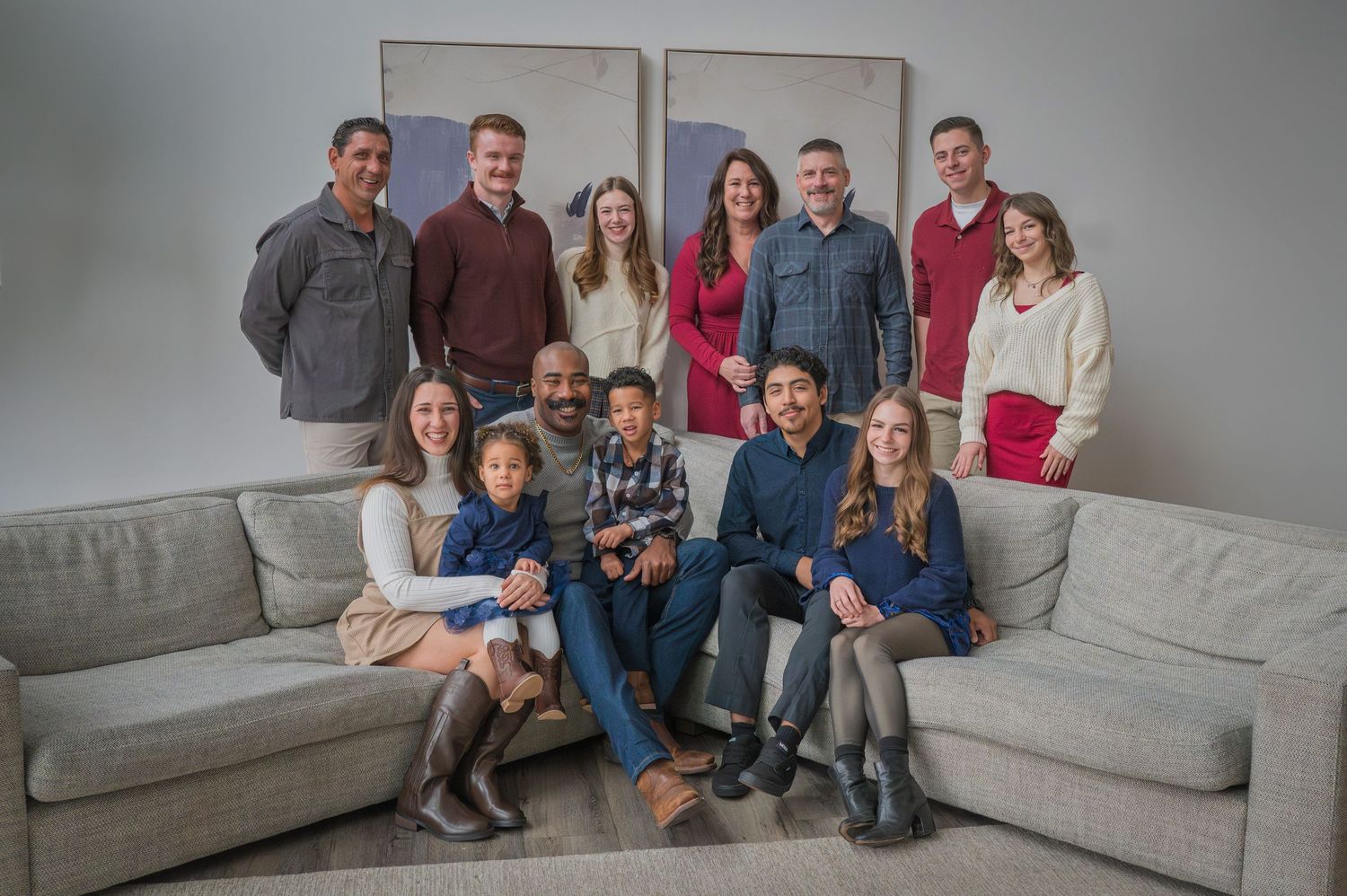 A casual family portrait of people gathered together on a sectional grey couch in a modern setting by Pigeon Forge TN Photographer.