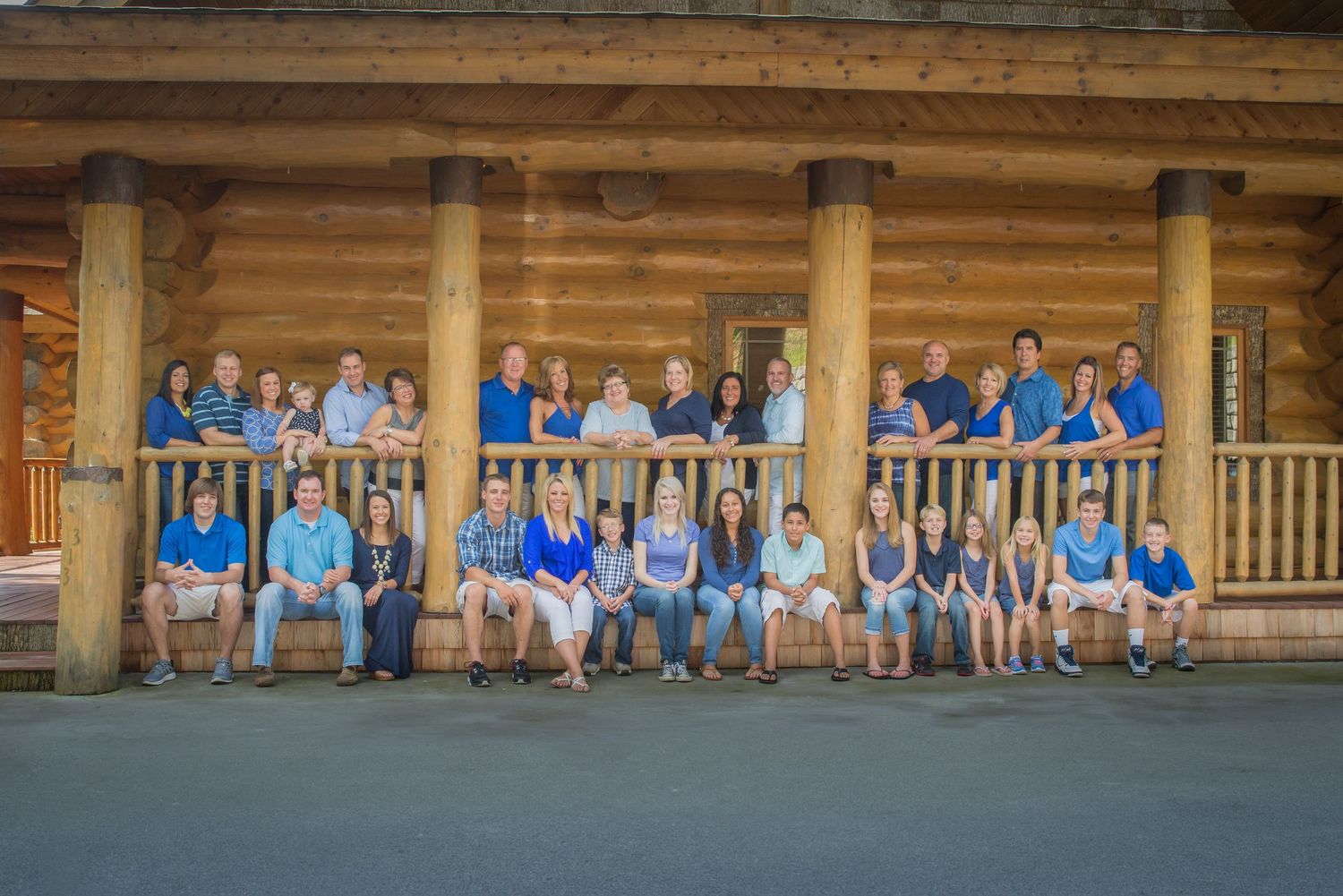 A large reunion in coordinated blue attire sits on a rustic wooden porch of a log cabin Pittman Center TN.
