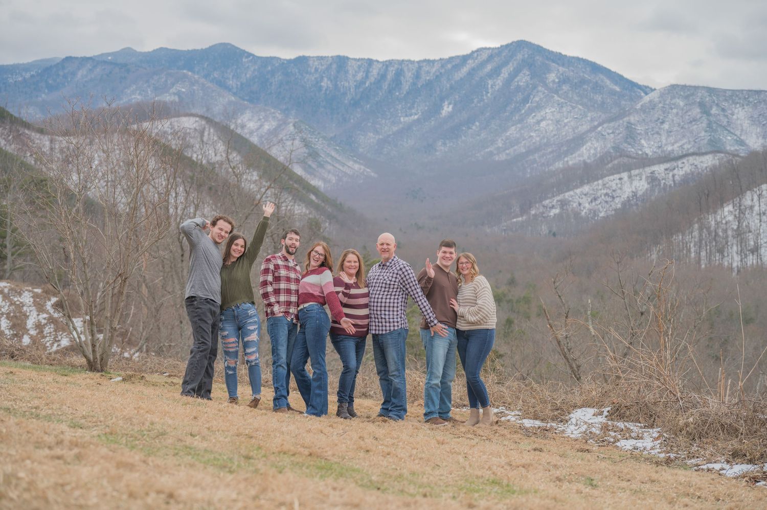 A group stands together on a hilltop overlook with snow-capped mountain peaks in the scenic winter landscape by Gatlinburg TN Photographers.