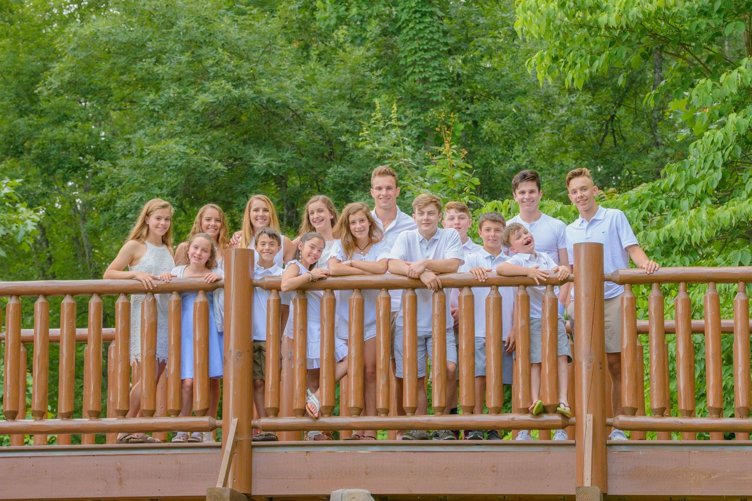 A group in coordinated light purple and white outfits stands together on a wooden deck bridge in a lush green setting in Sevierville TN.