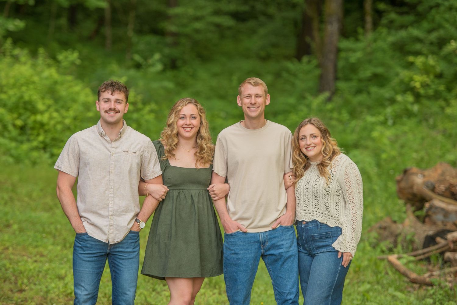 Family of four people standing together outdoors on grass with green forest background at lake house rental in Dandridge tn.