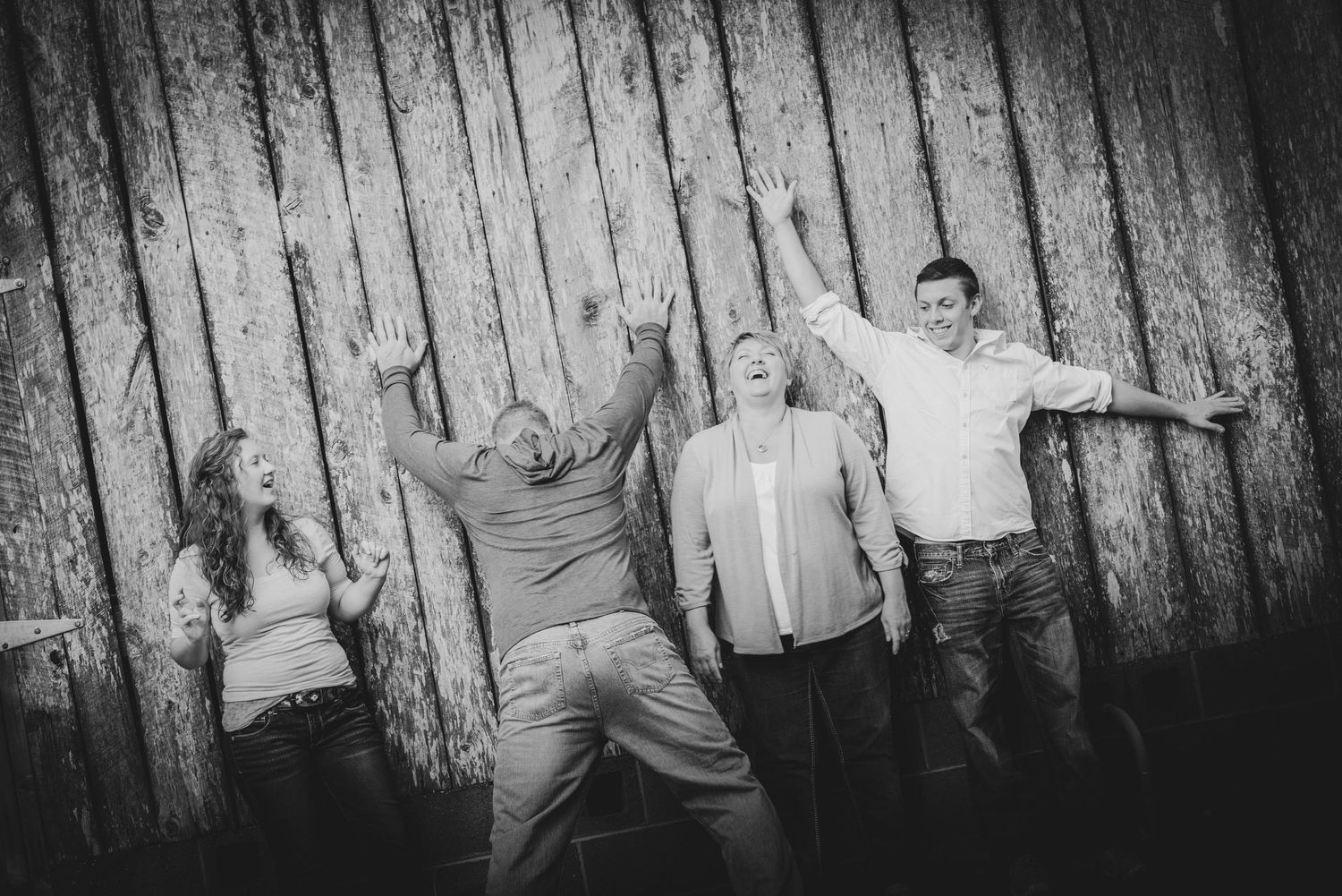 Black and white artistic photo of a group posed casually leaning against a rustic wooden wall outdoors in Gatlinburg TN.