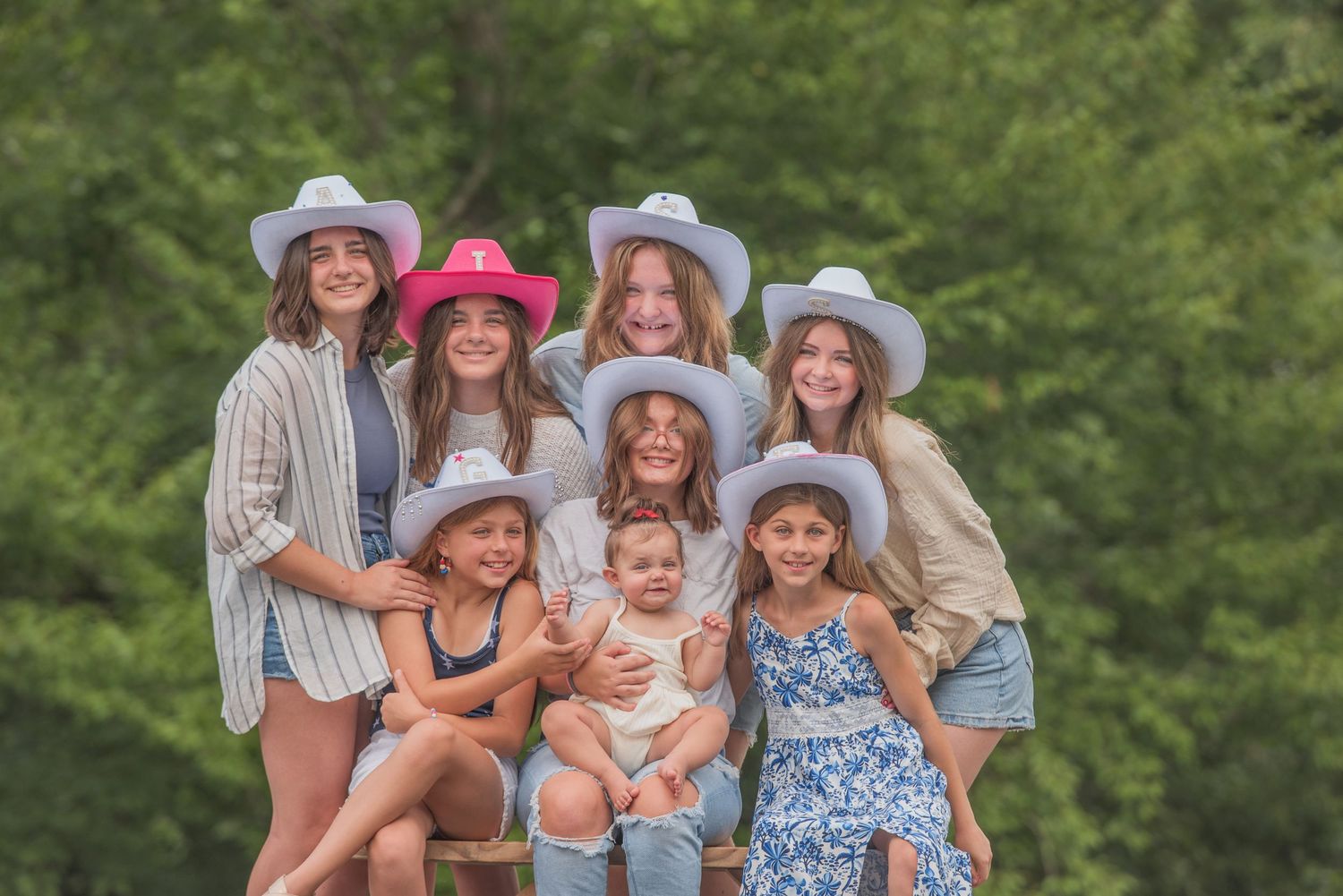 A group of cousins wearing cowboy hats and casual summer attire pose together outdoors at their rental in Sevierville TN.