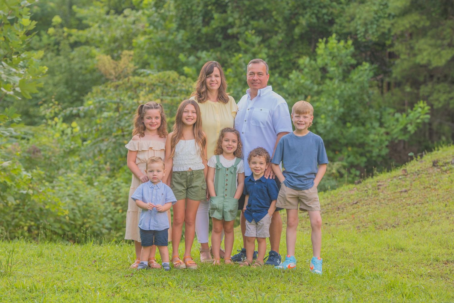 Group standing together outdoors on a grassy hill with lush green foliage in the background at the cabin rental Sevierville tn.